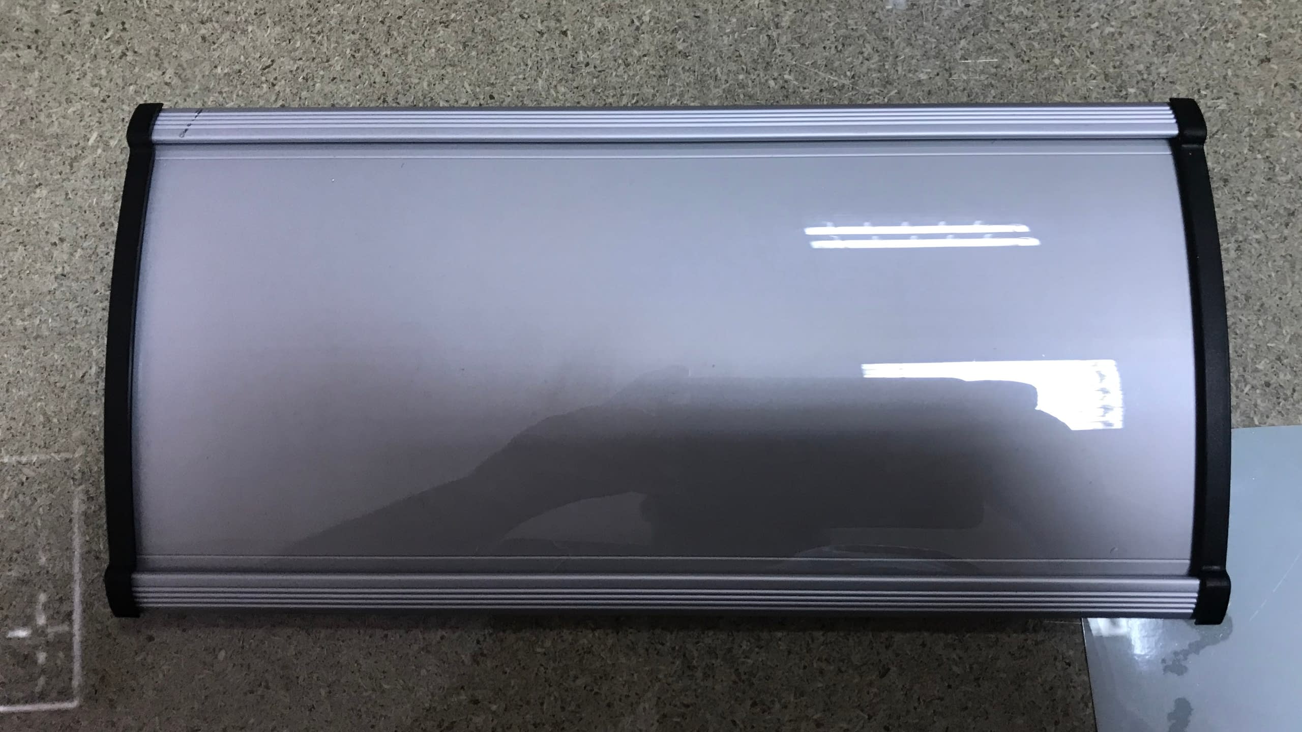 Празна алуминиева табела с извит профил и черни страници, готова за поставяне на надпис или лого.