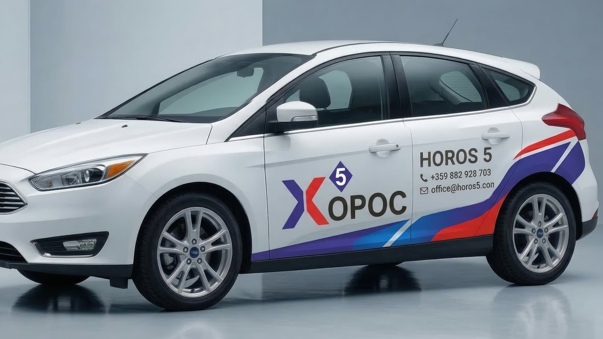 Автомобил с частично брандиране на Хорос 5, включващо лого отпред, телефон и имейл на задната врата, подчертани със сини и червени ленти.