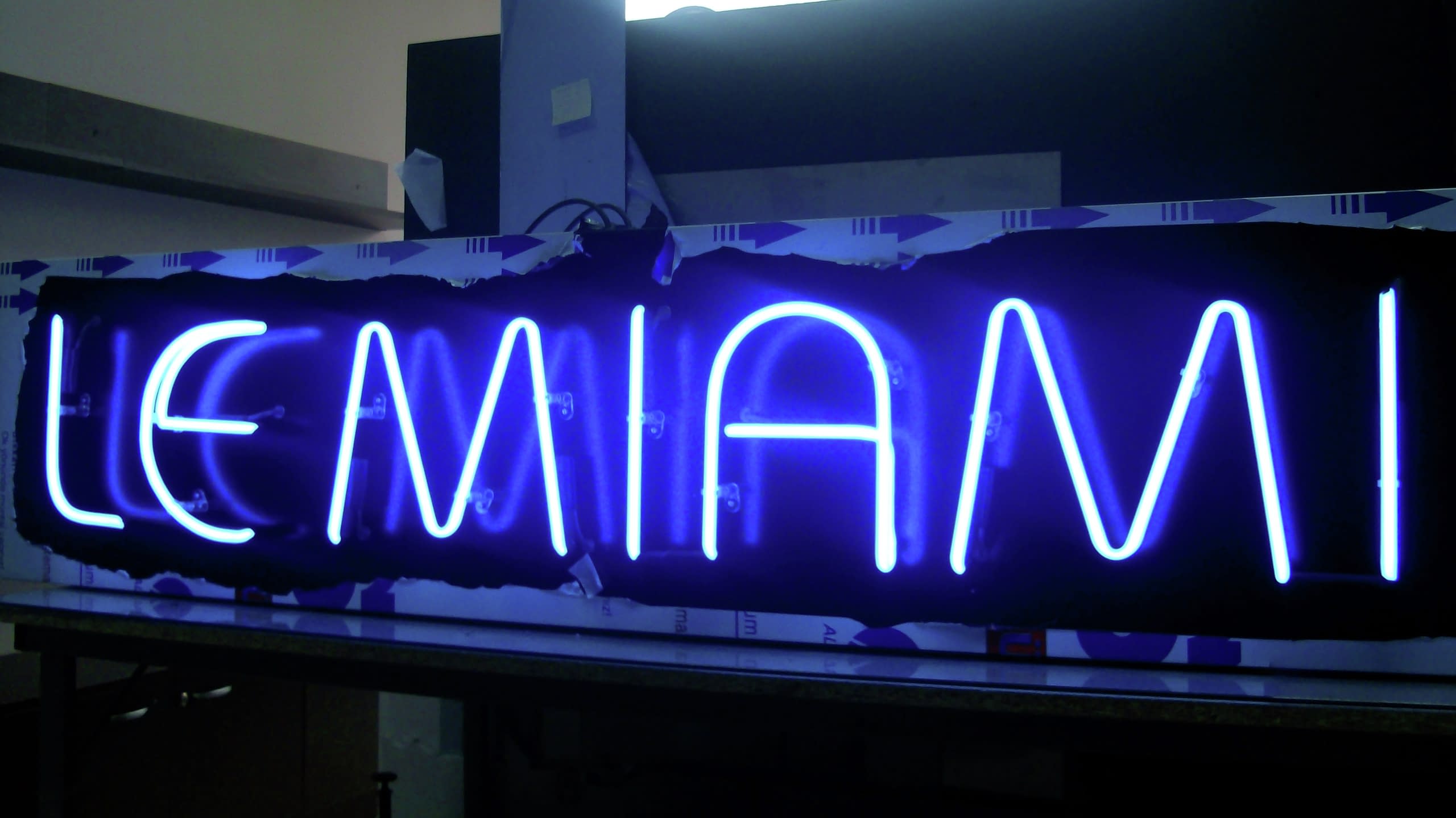 Процес на изработка на неонов надпис "LE MIAMI", светещ в наситеносин цвят.