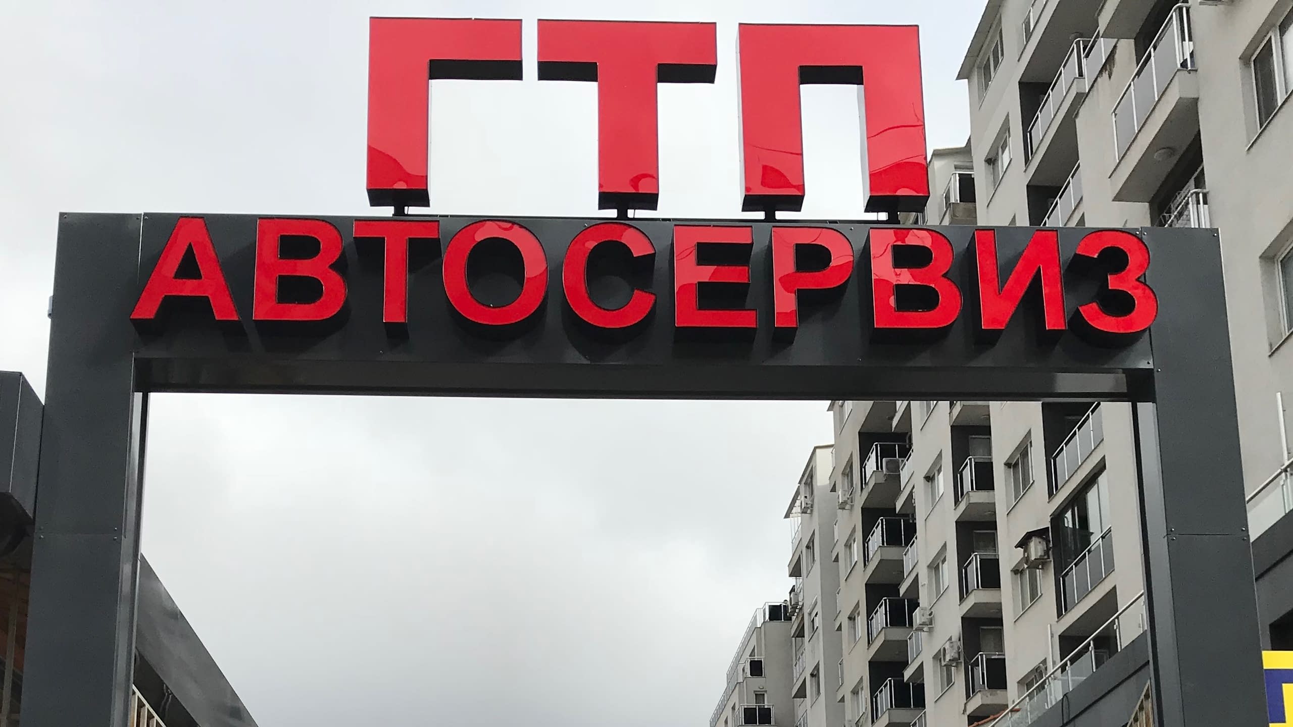 Голяма рекламна табела с яркочервени светещи обемни букви от плексиглас с надпис "ГТП АВТОСЕРВИЗ", монтирана на метална конструкция.