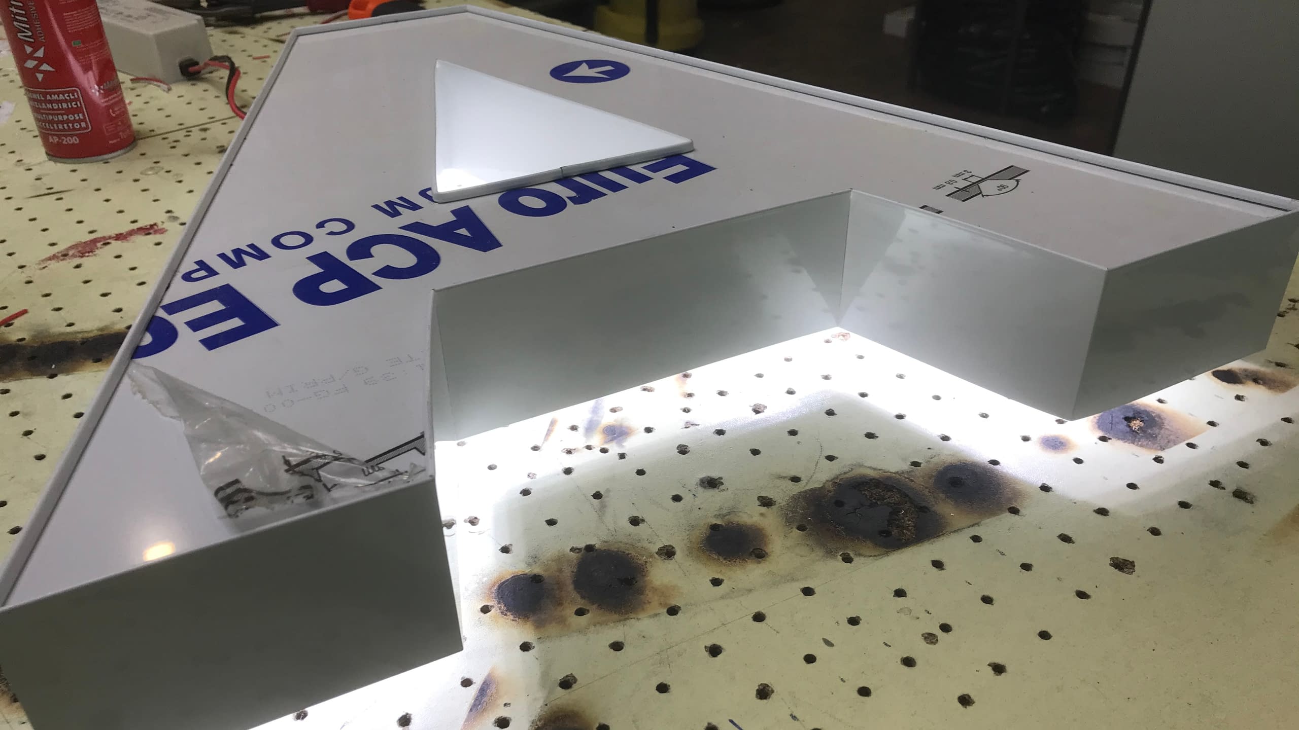 Готова светеща обемна буква А с контражурно осветление (хало ефект), поставена на работна маса.