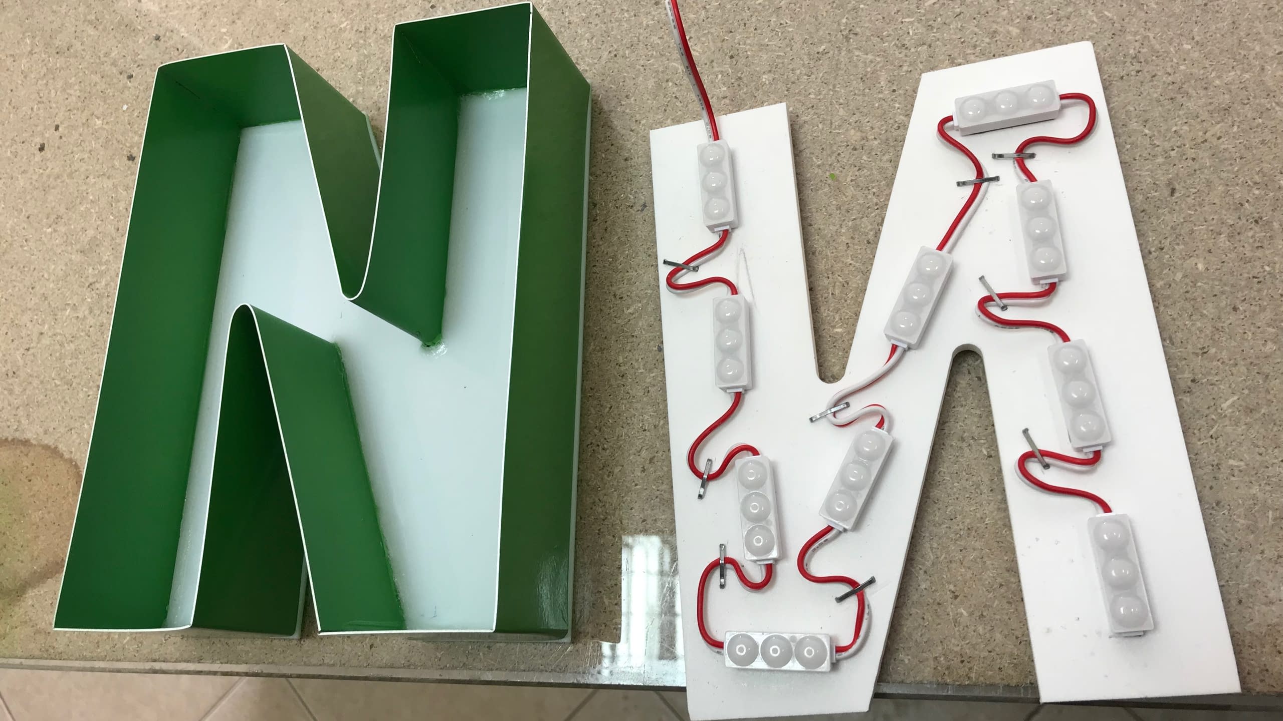 Компоненти за изработка на светеща обемна буква М: зелен метален борд и гръб от плексиглас с вградени LED модули.