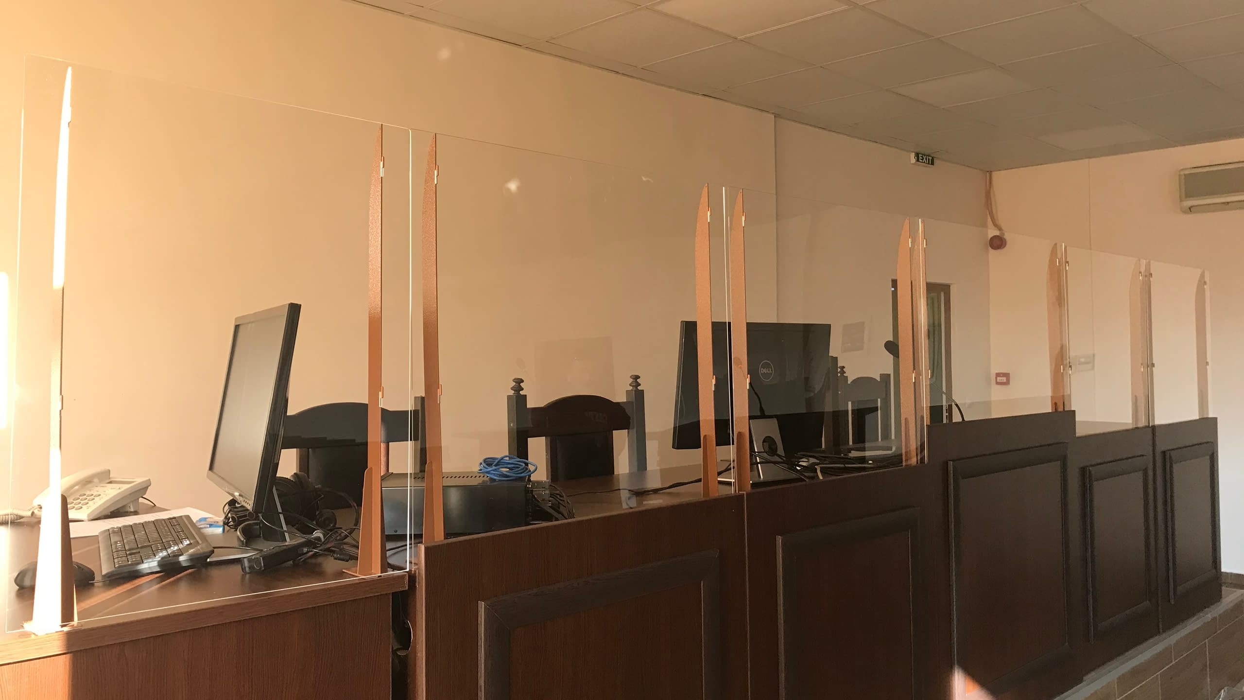 Работни места в институция, оборудвани с високи предпазни прегради от плексиглас за разделяне на бюрата.