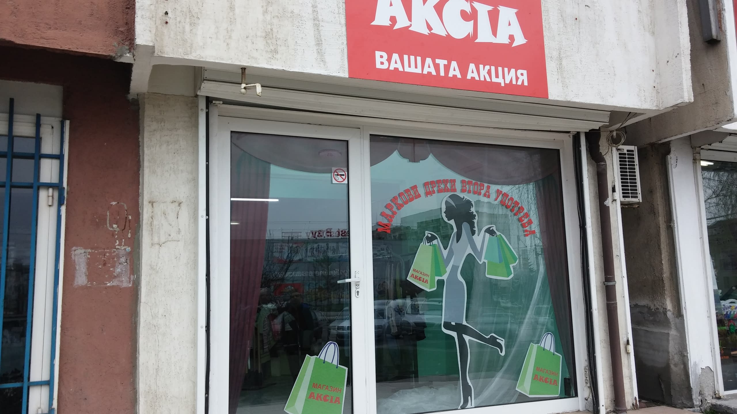 Стъклена витрина на магазин, облепена с фолио със силует на жена и пазарски чанти.