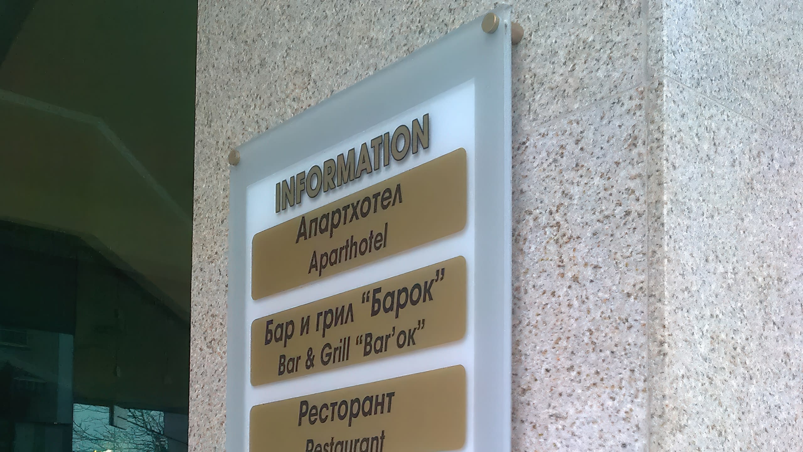 Близък план под ъгъл на информационна табела, показващ обемните букви и начина на закрепване към стената с държачи.