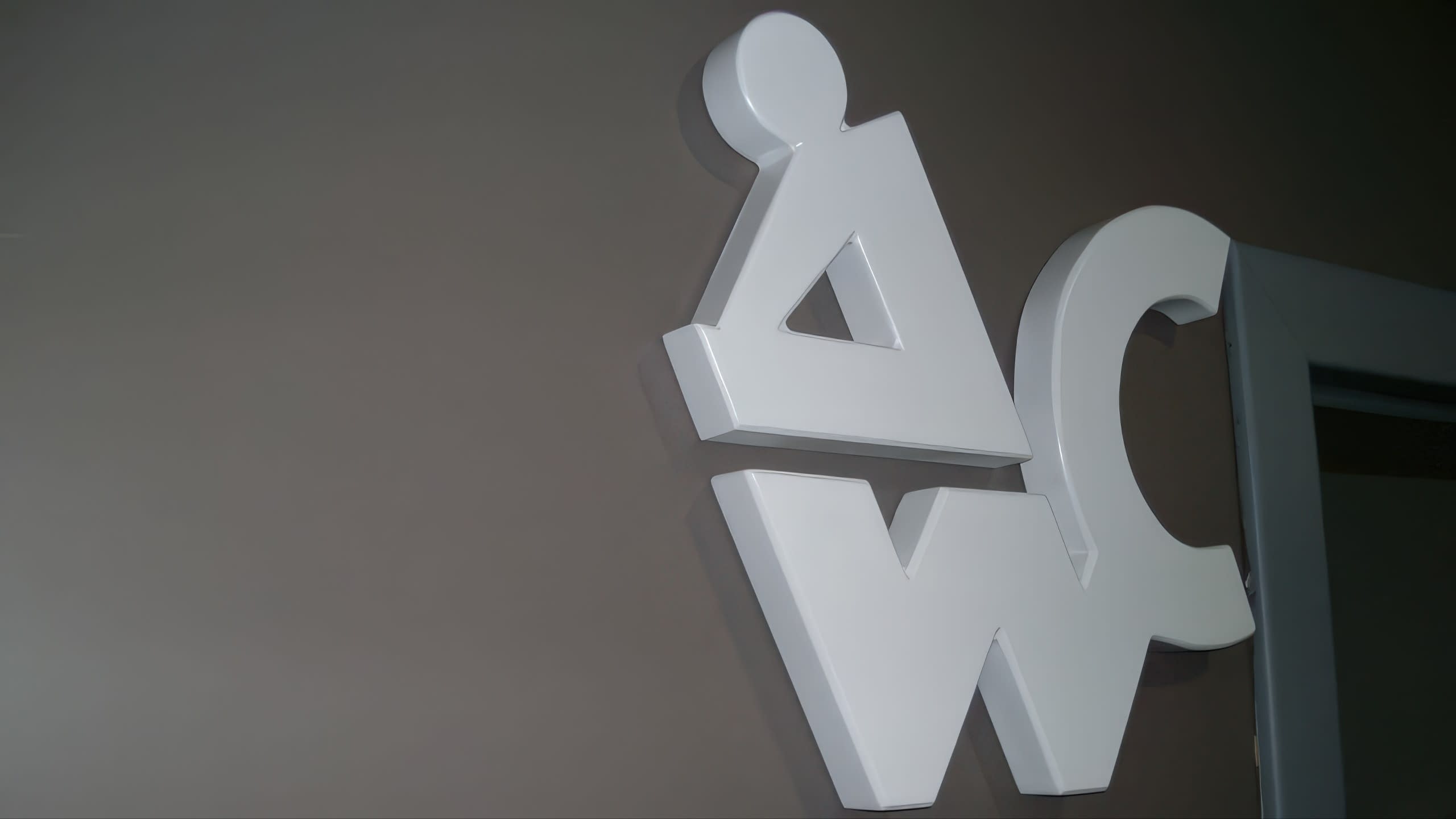 Близък план на бели обемни символи за тоалетна, поставени на стена до рамка на врата.