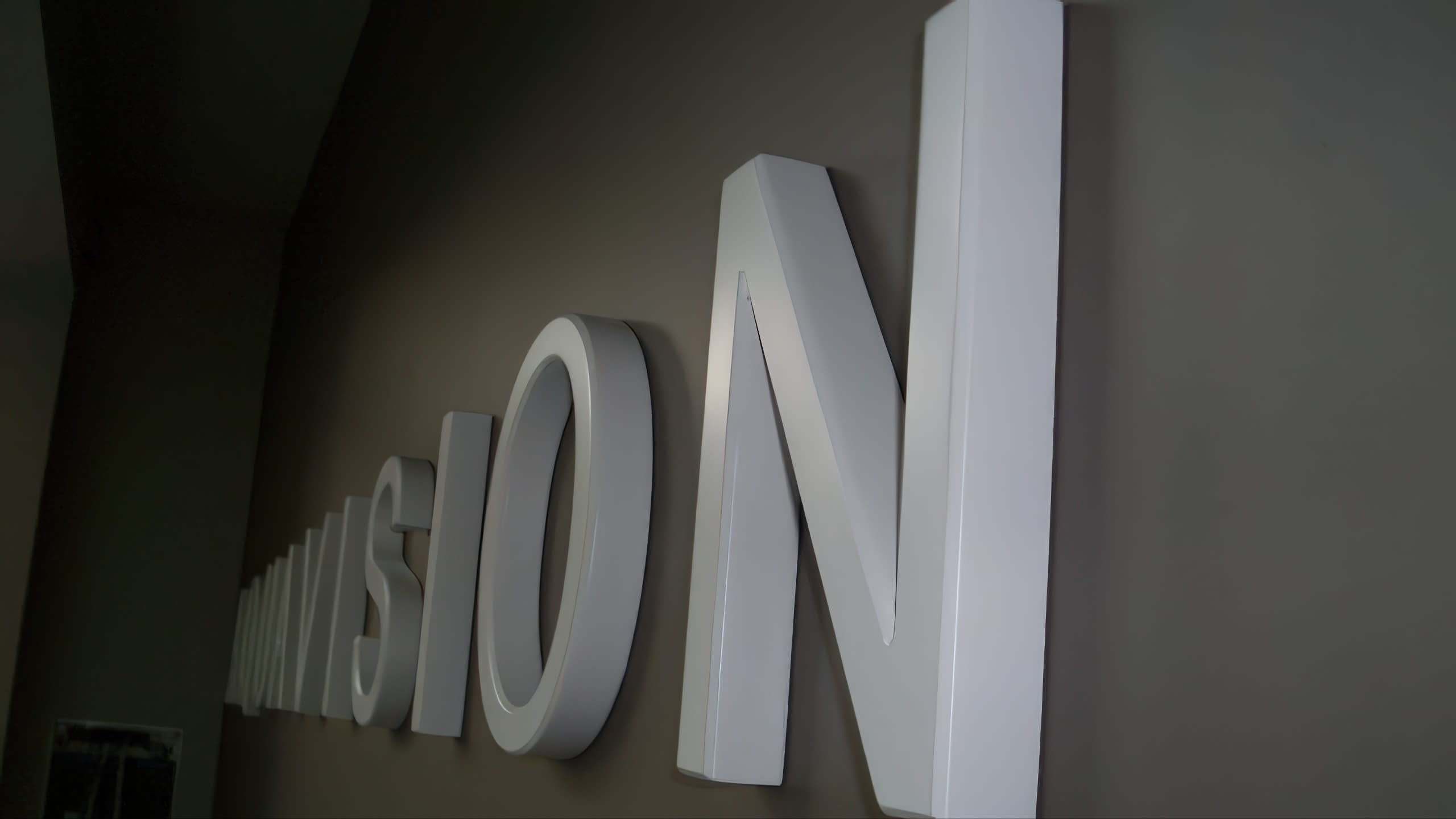 Перспективен изглед на обемни букви, монтирани на стена, който подчертава триизмерния им ефект.