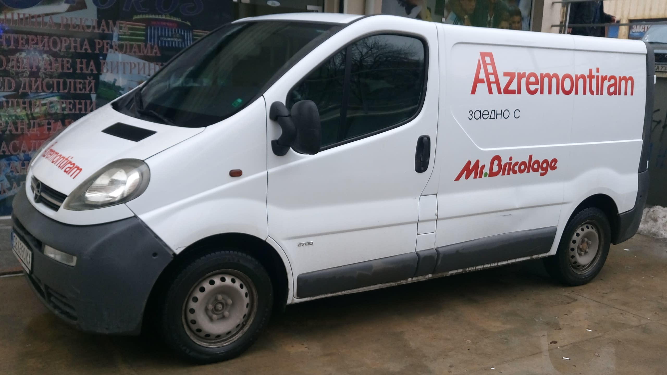 Цялостен изглед на бял служебен бус с червени фирмени надписи отстрани и на предния капак.