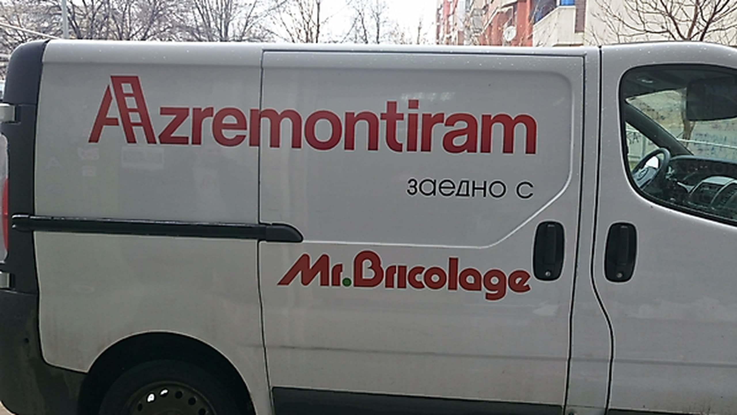 Близък план на страничната врата на бял бус с червени надписи "Azremontiram" и "Mr.Bricolage".