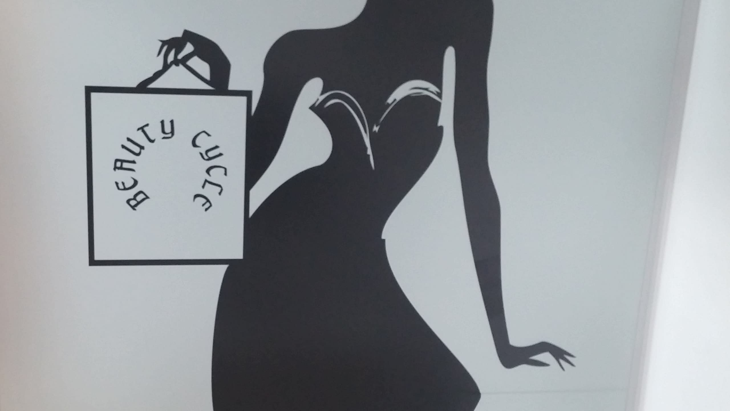 Близък план на детайл от графичен стикер, изобразяващ торса на жена и чанта за пазаруване с текст.