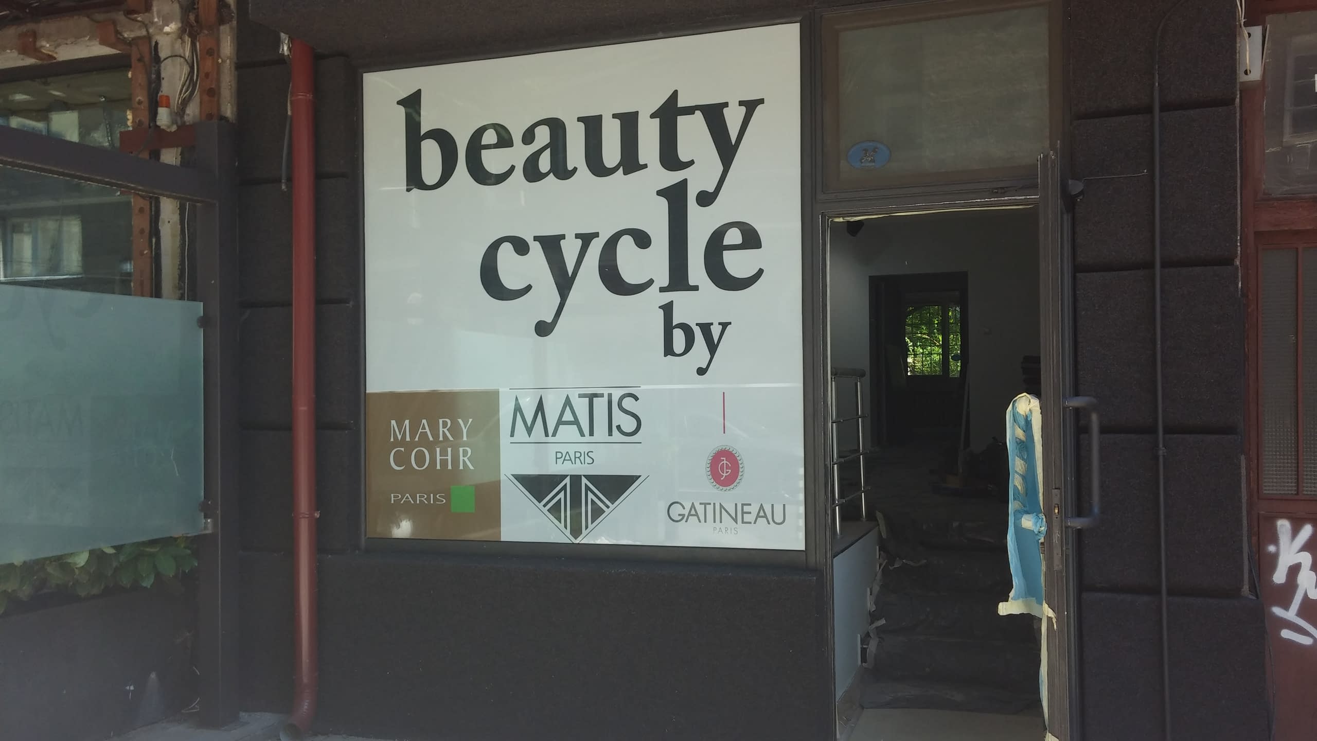 Витрина на търговски обект, облепена с бяло фолио с надпис „beauty cycle“ и лога на партньорски марки.