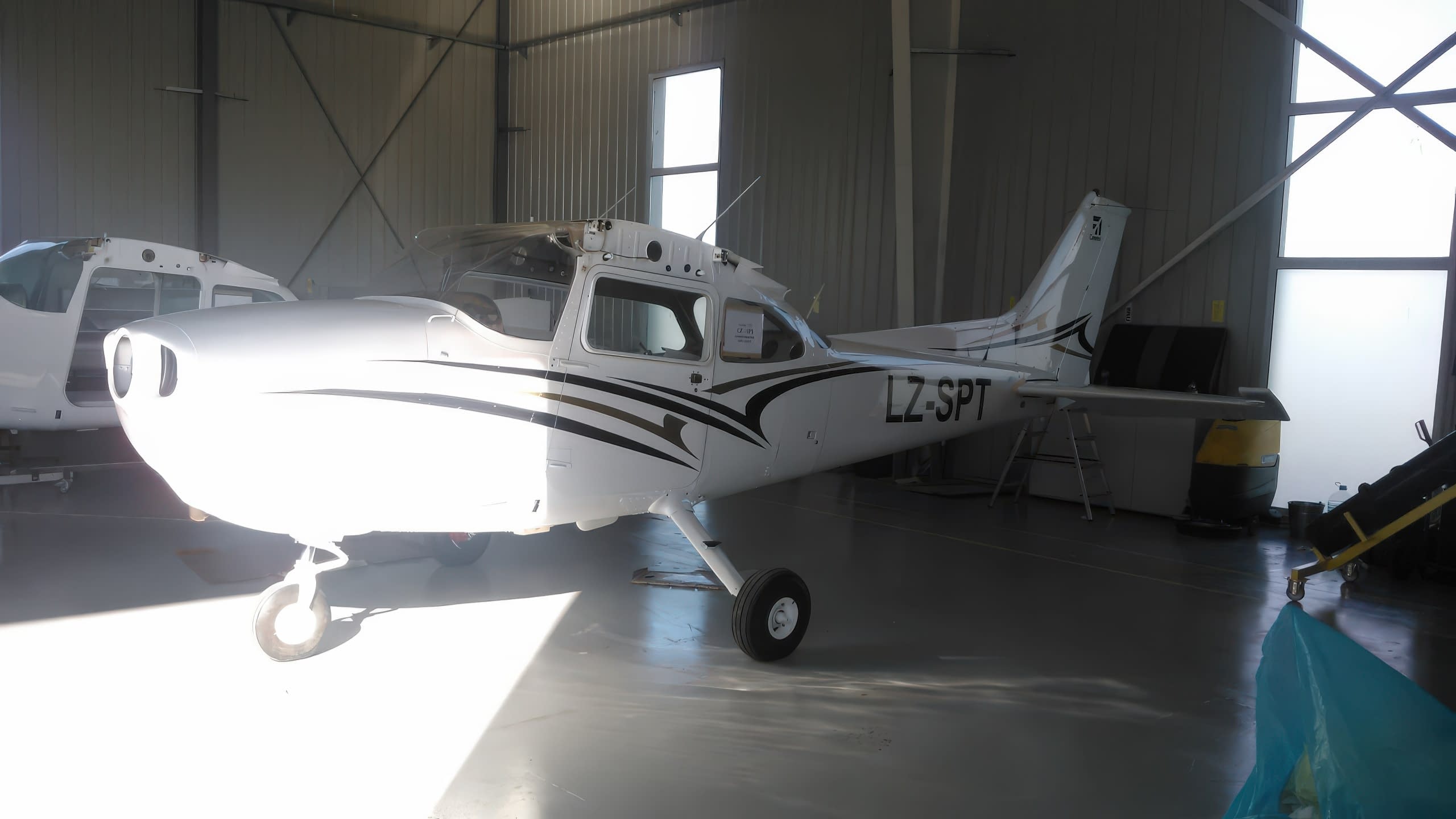 Цялостен изглед на самолет с декоративни стикери, намиращ се в хангар.