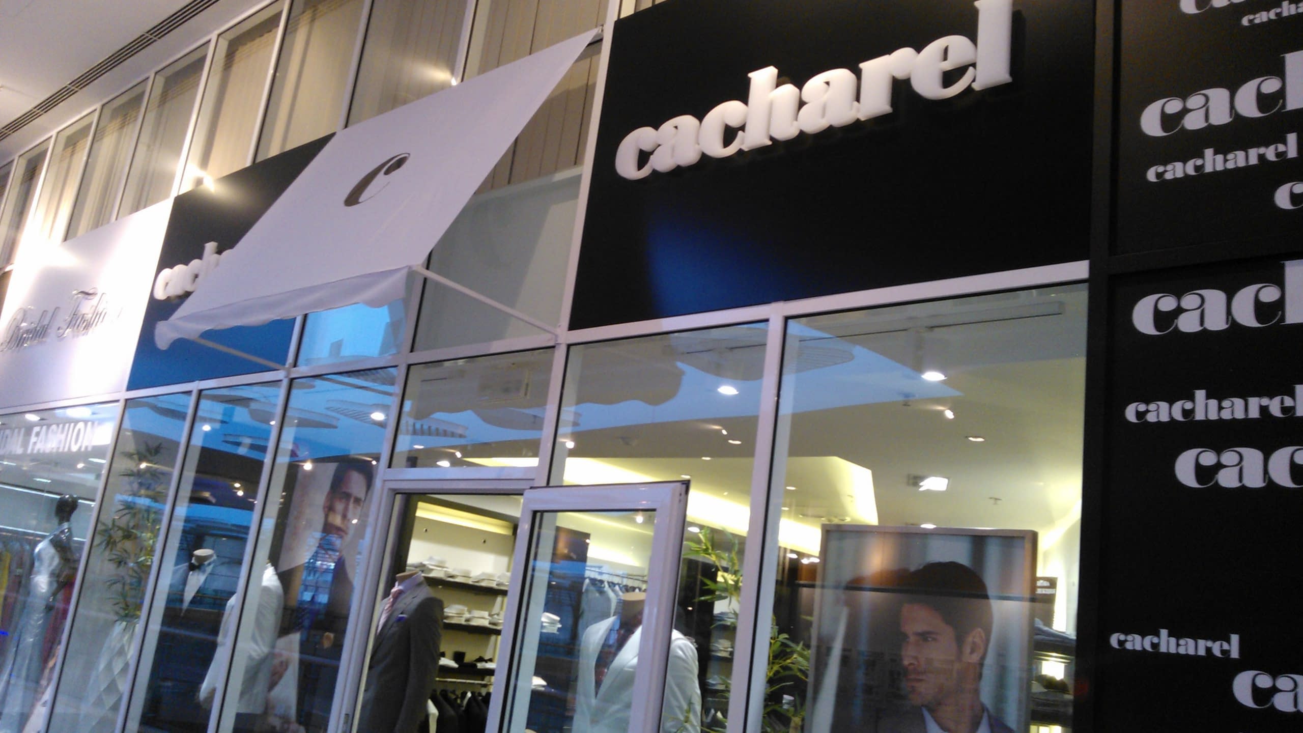 Вход на магазин Cacharel, над който има голяма табела с обемни букви и декоративни елементи с логото на марката.