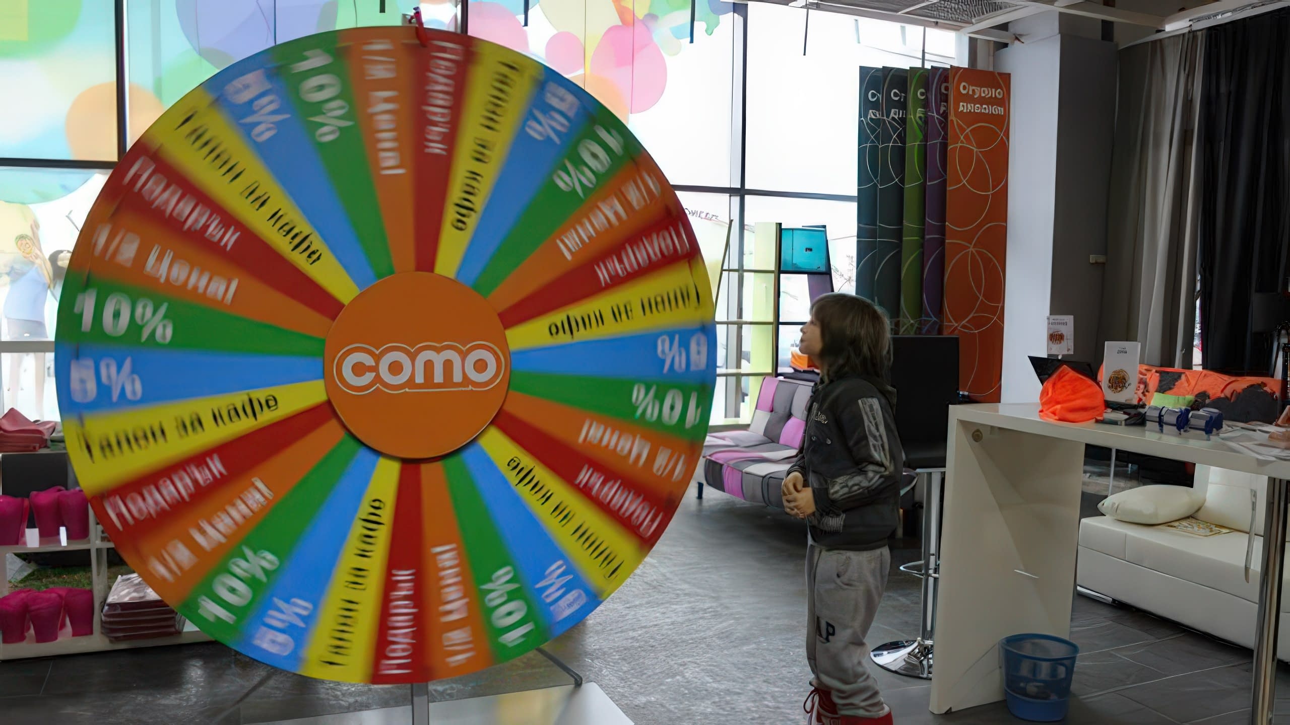 Посетител на магазин наблюдава как се върти голямо и шарено колело с награди.