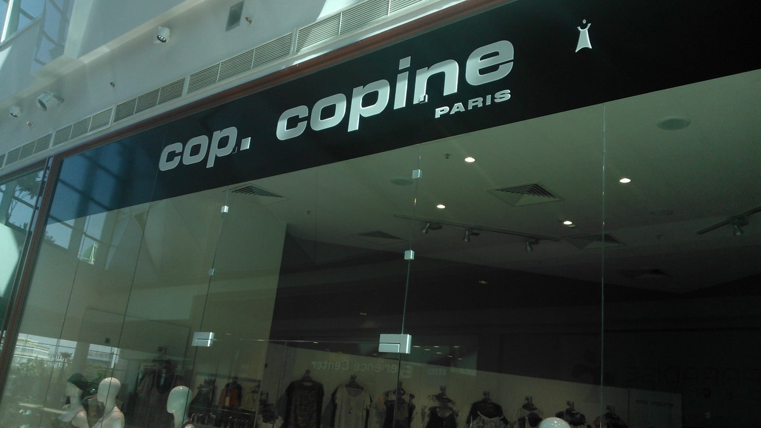 Черна табела с бял надпис „cop. copine PARIS“, монтирана над стъклена витрина на магазин.