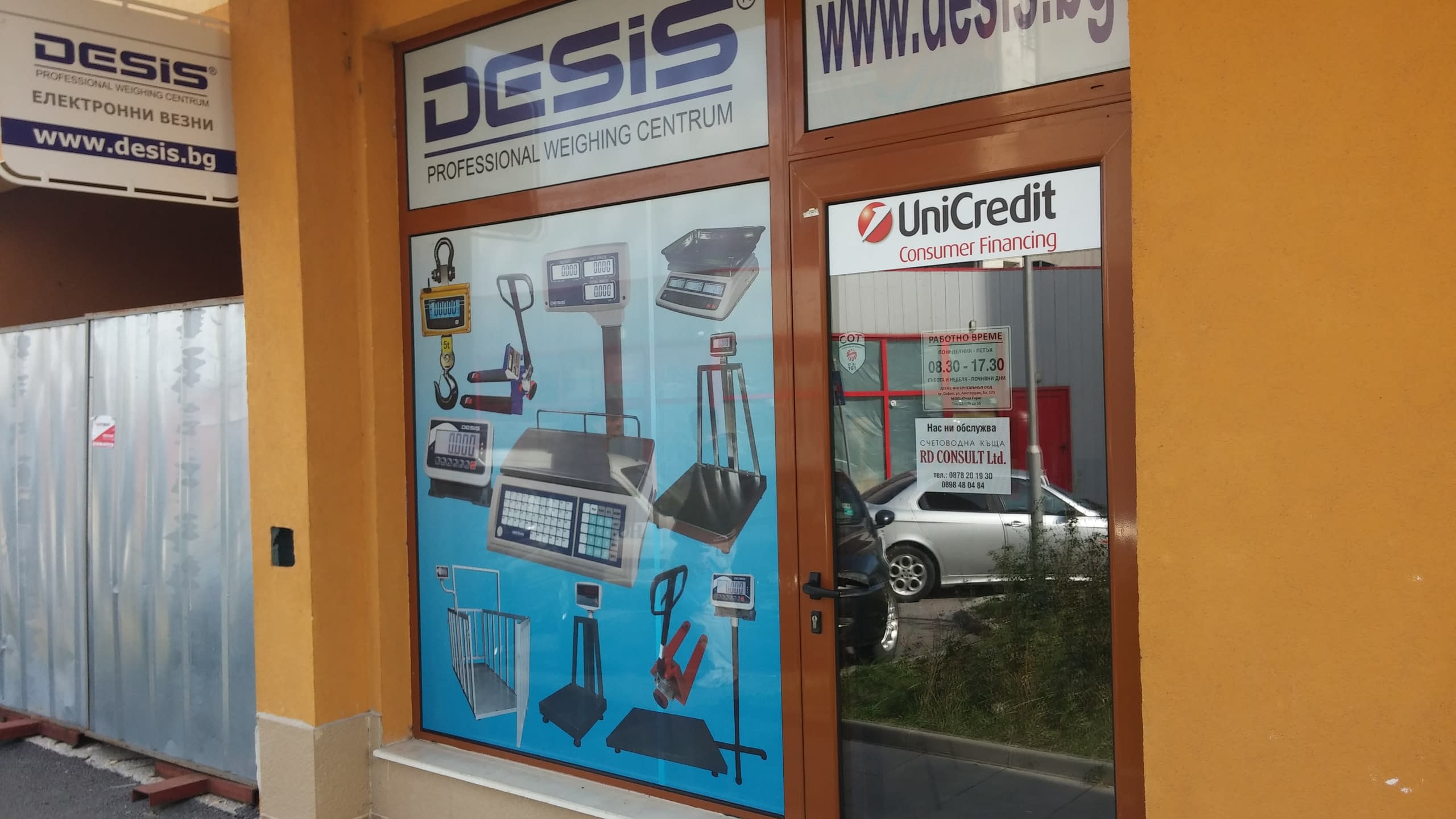 Вход на офис с облепена витрина, на която са изобразени различни видове електронни везни и кантари.