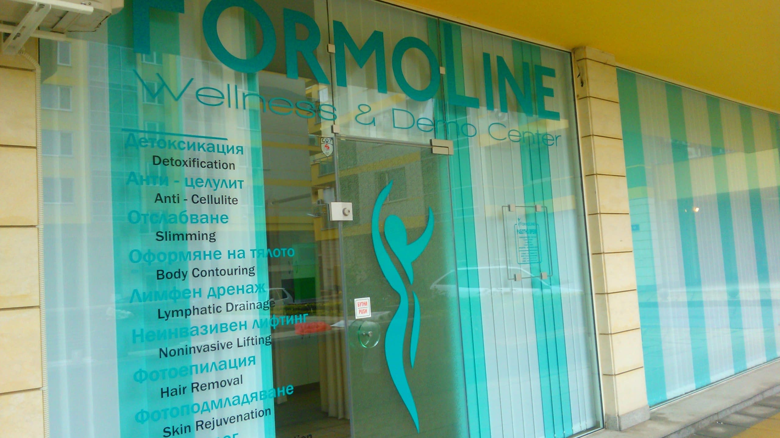 Стъклена витрина на уелнес център, облепена с фолио в зелени нюанси и надписи на български и английски език.