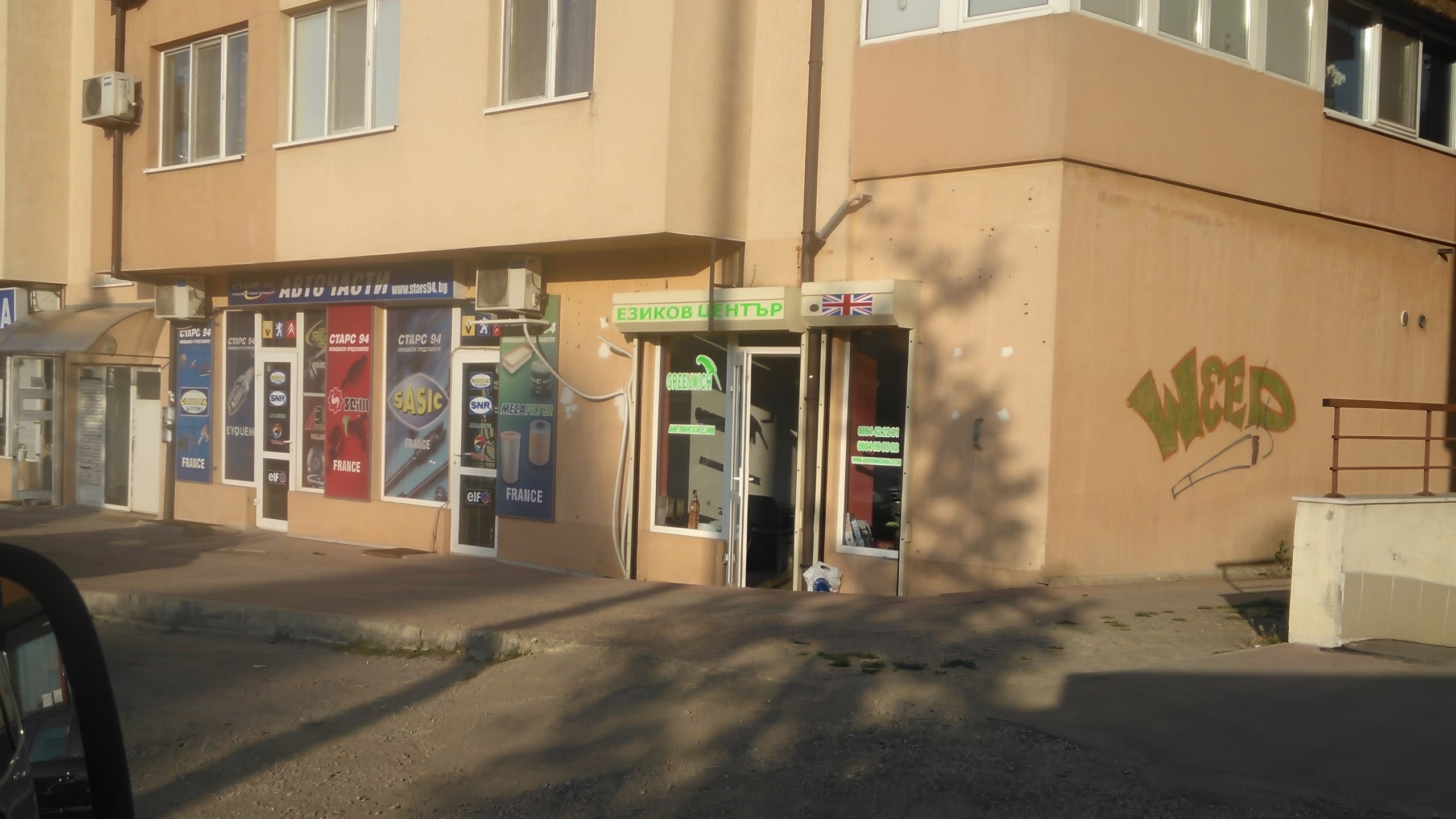 Изглед от улицата към вход на езиков център, разположен на партерния етаж на сграда.