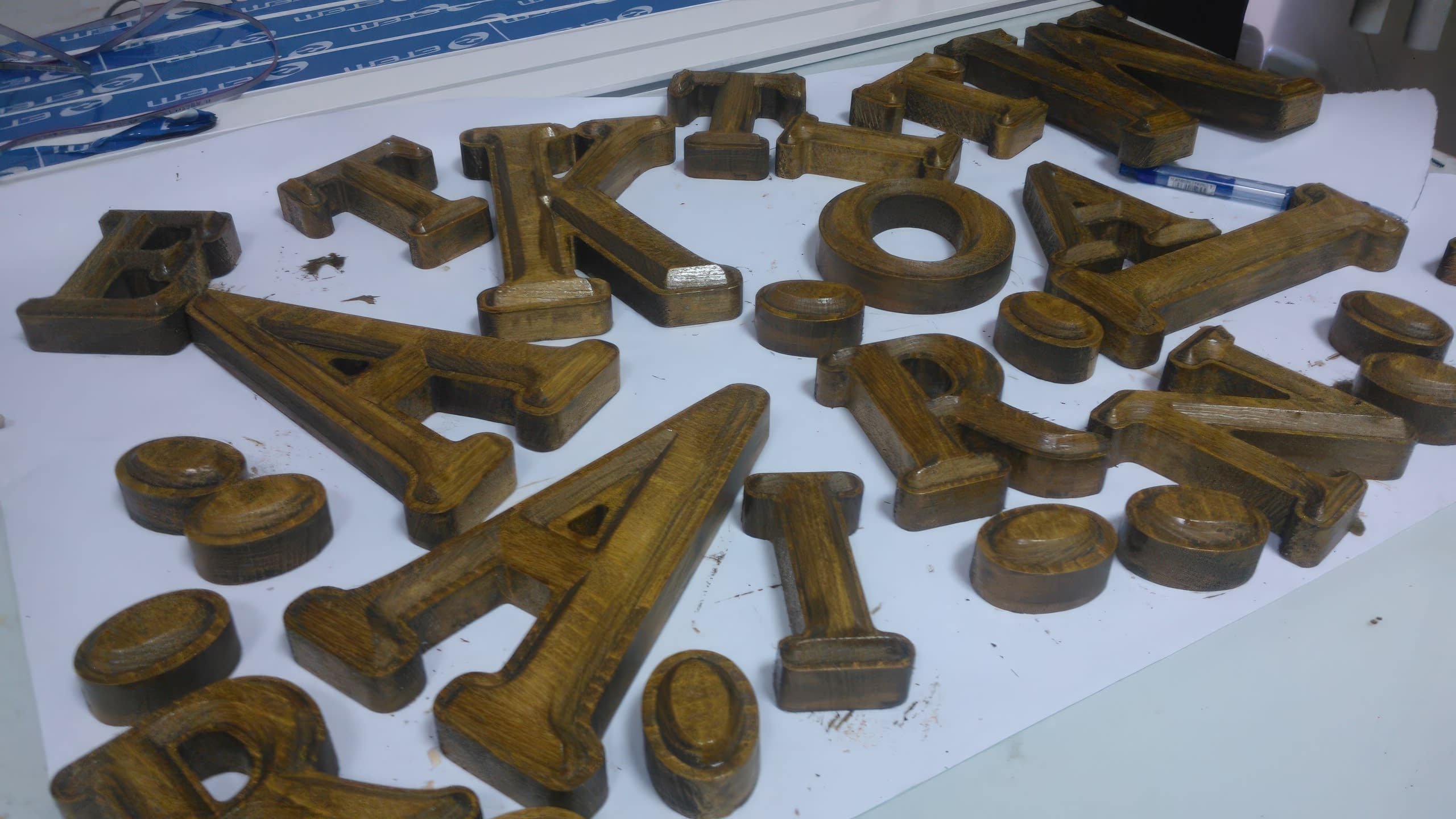 Обемни букви с дървесна текстура, разпръснати върху работна маса преди да бъдат сглобени.