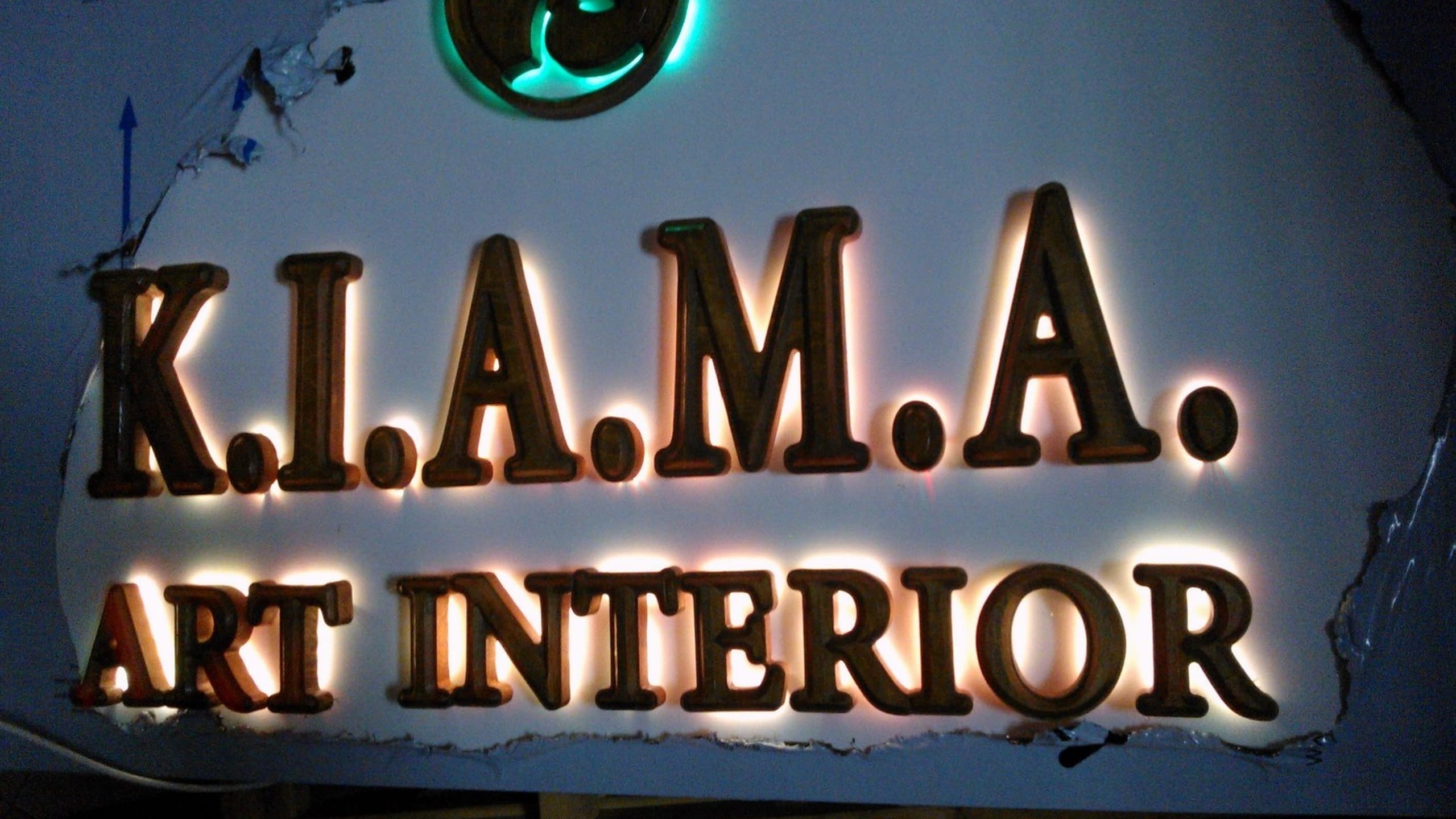 Светеща табела с букви с дървесен ефект, осветени с топла бяла и зелена светлина, по време на тест в работилница.