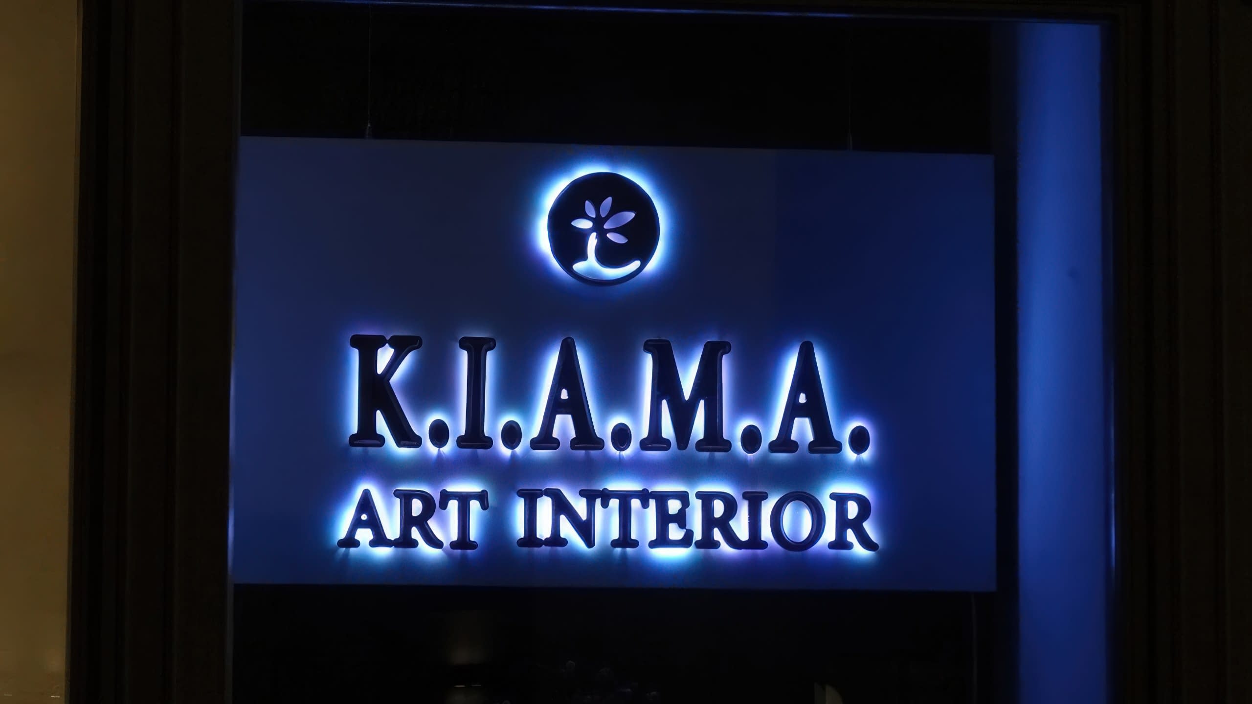 Финален изглед на интериорен надпис K.I.A.M.A. Art Interior, монтиран на тъмна стена и осветен в студено синьо.