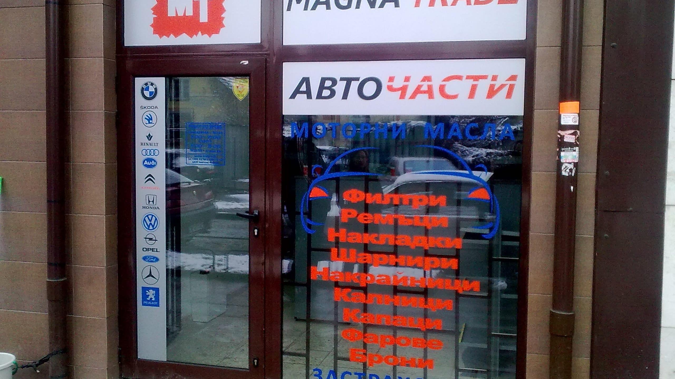 Витрина и врата на магазин за авточасти, облепени с рекламно фолио с логото и името на фирмата, както и списък с предлагани части.