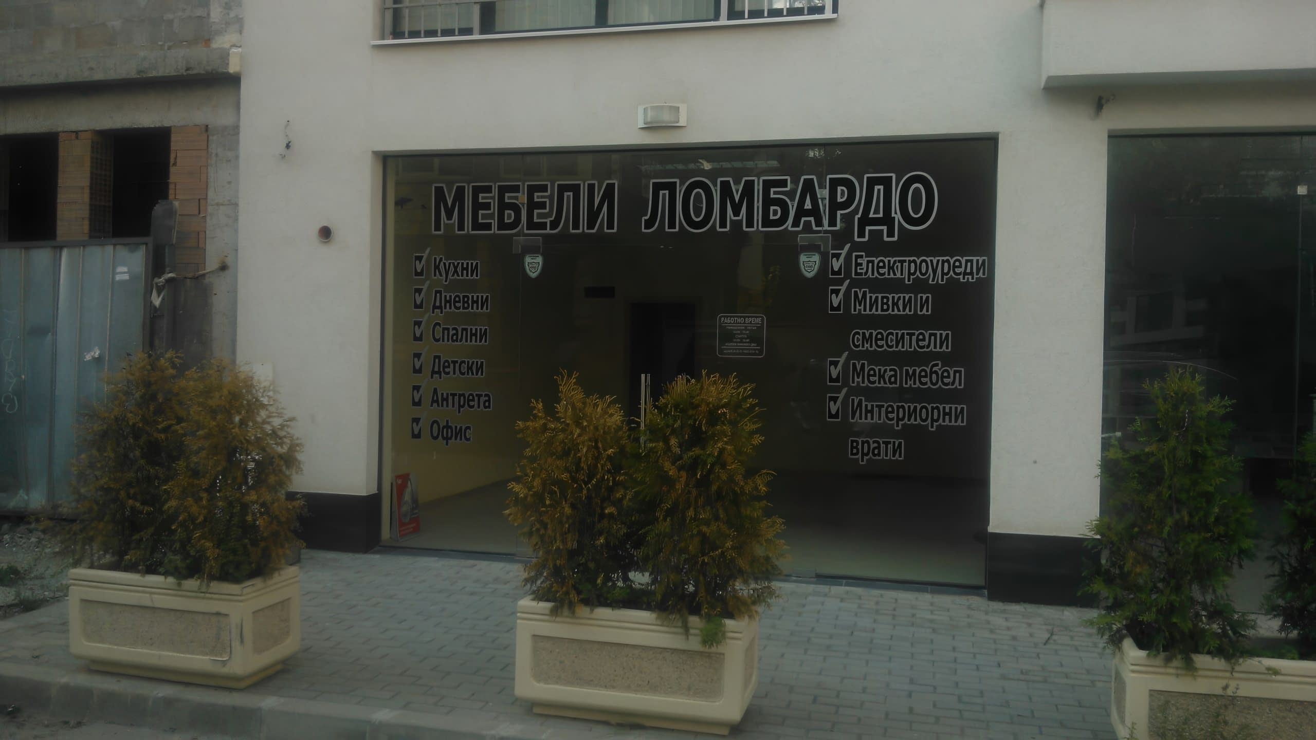 Надписи от бяло фолио върху витрината на мебелен магазин, зад които се вижда интериорът на магазина.