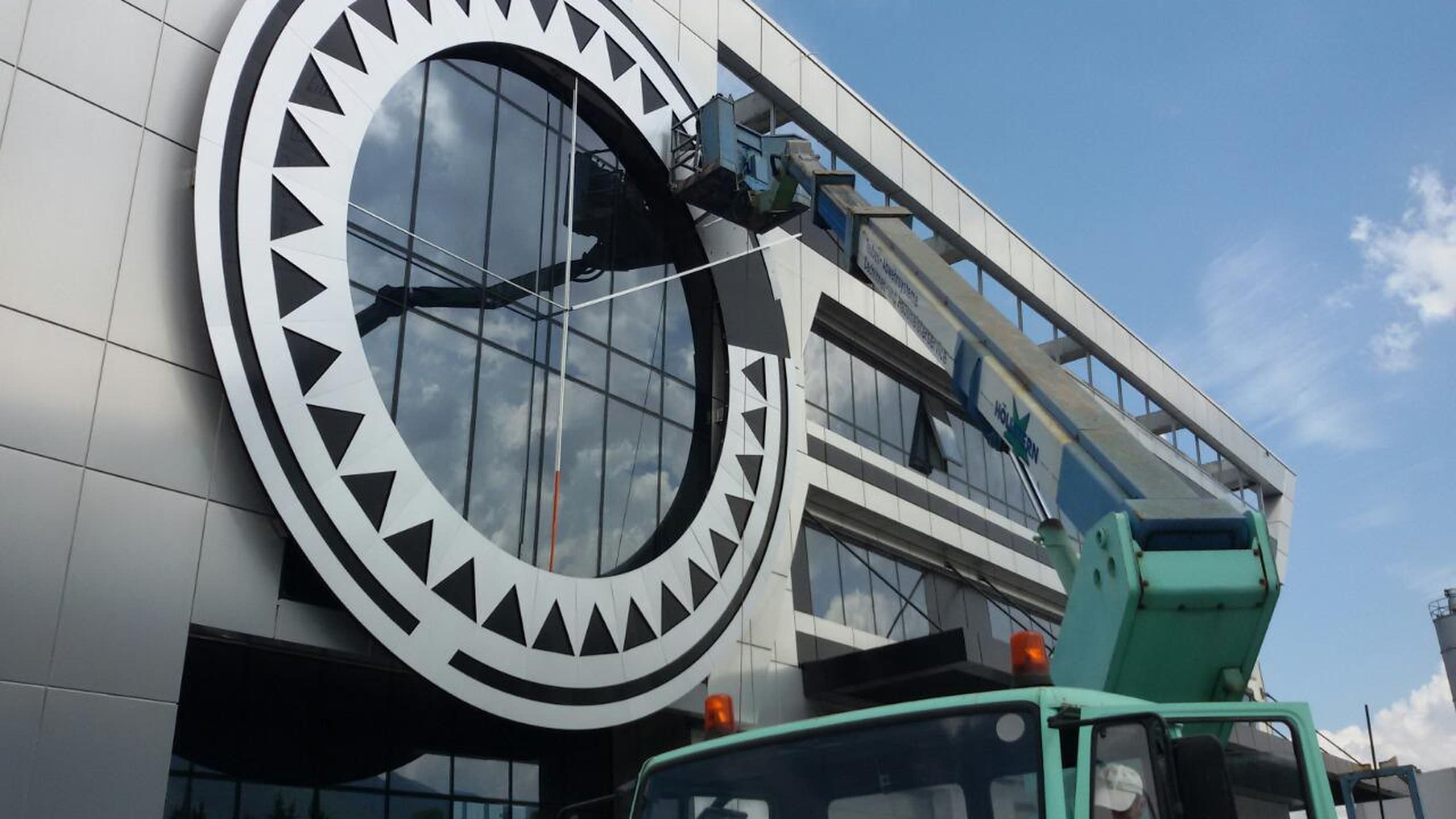 Монтаж на голям кръгъл декоративен елемент на фасада на сграда с помощта на вишка.