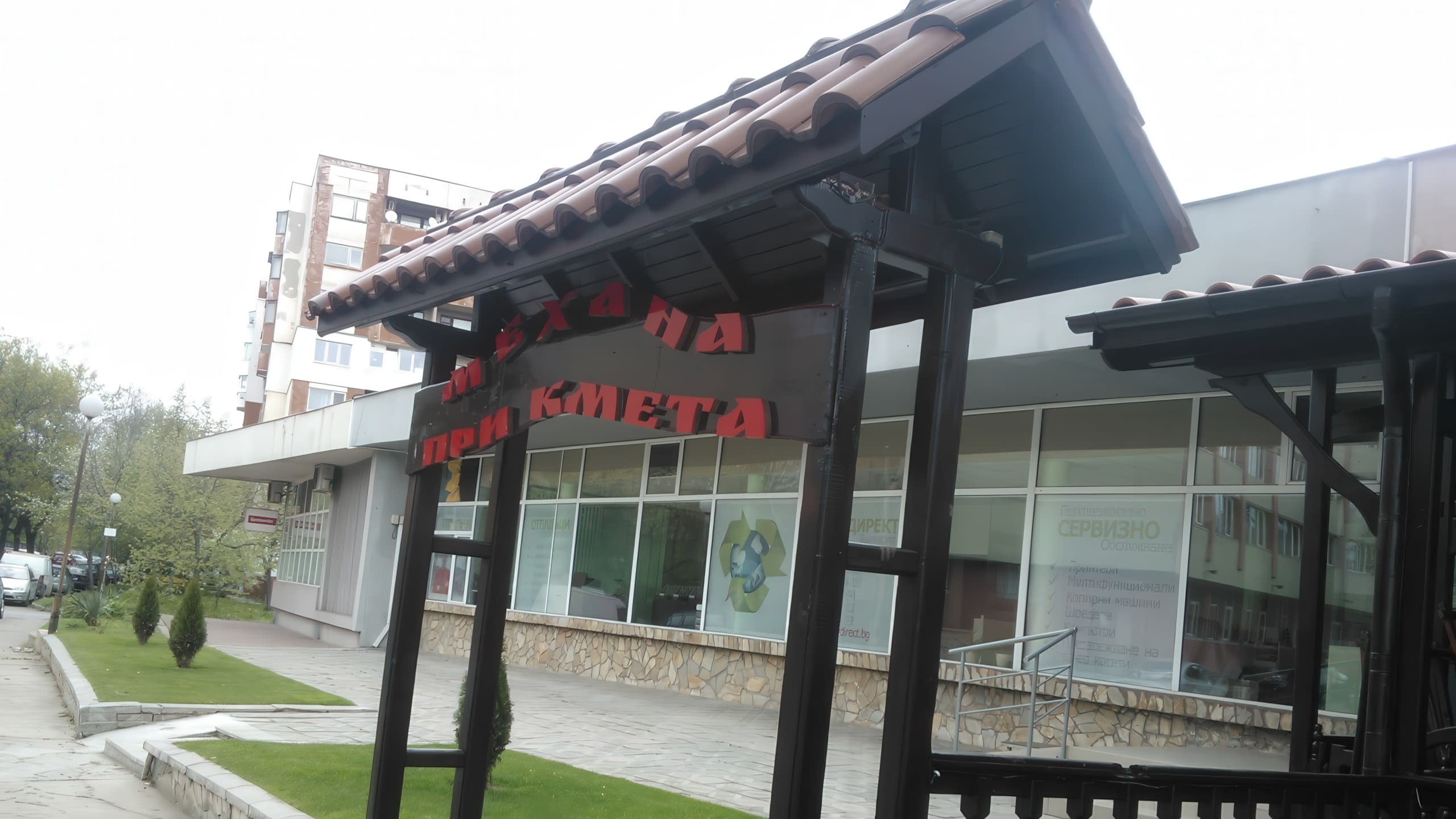 Дървена арка с керемиди и табела с надпис "Механа При Кмета" пред заведение.