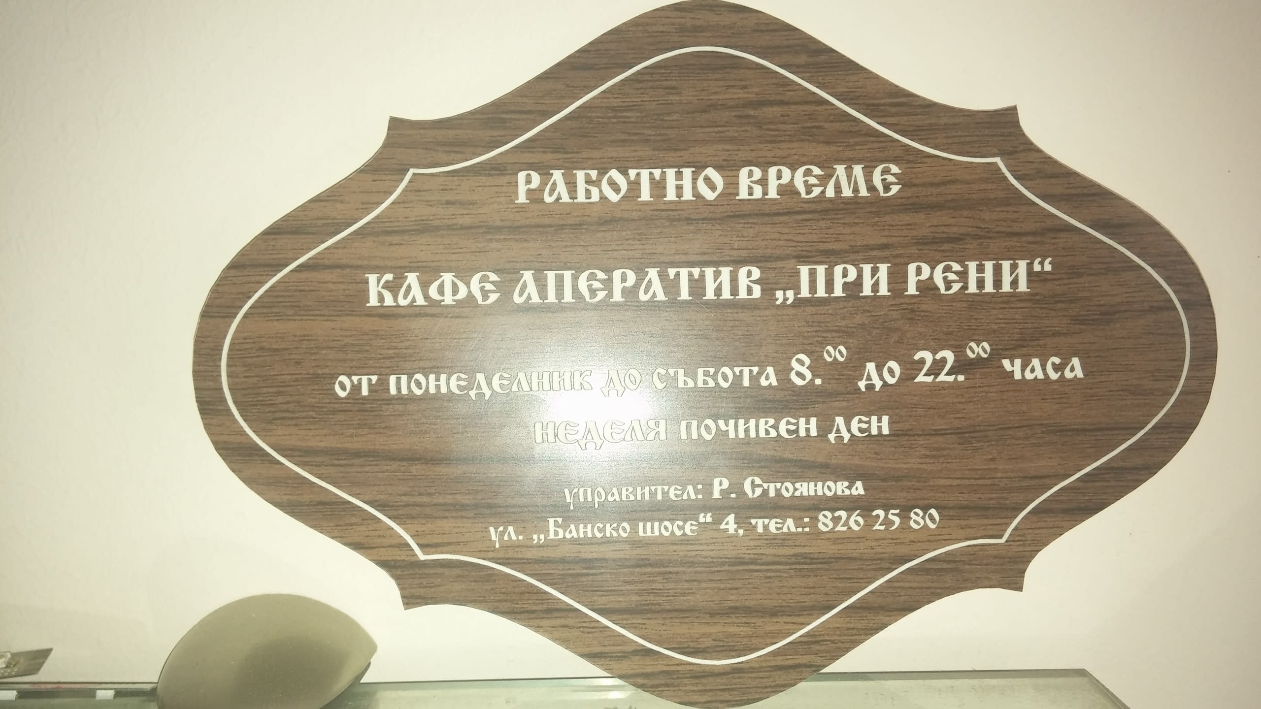 Табела с информация за кафене, заснета под ъгъл със светлинен отблясък на повърхността.