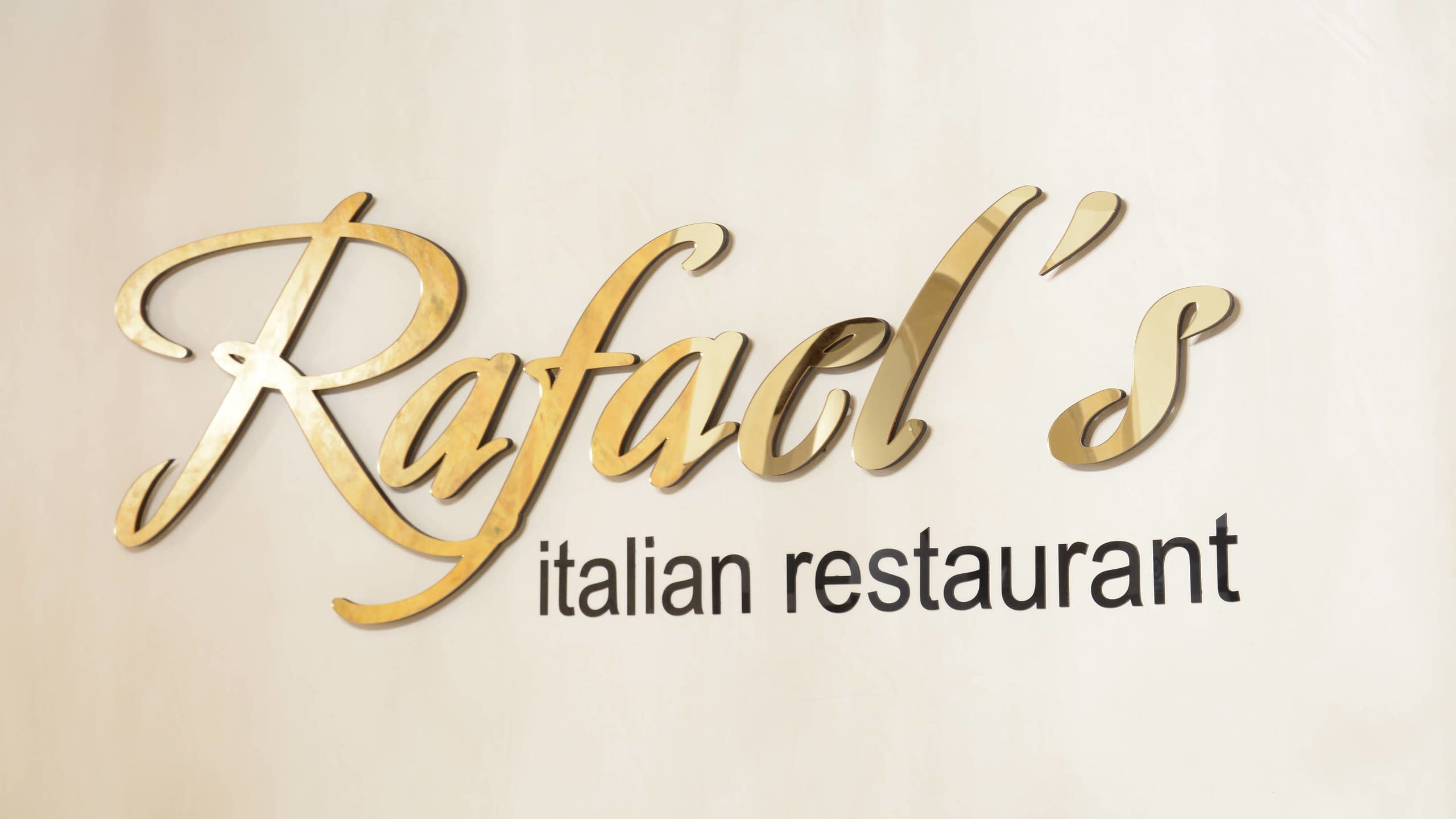Близък план на релефни букви със златиста огледална повърхност, изписващи "Rafael's".