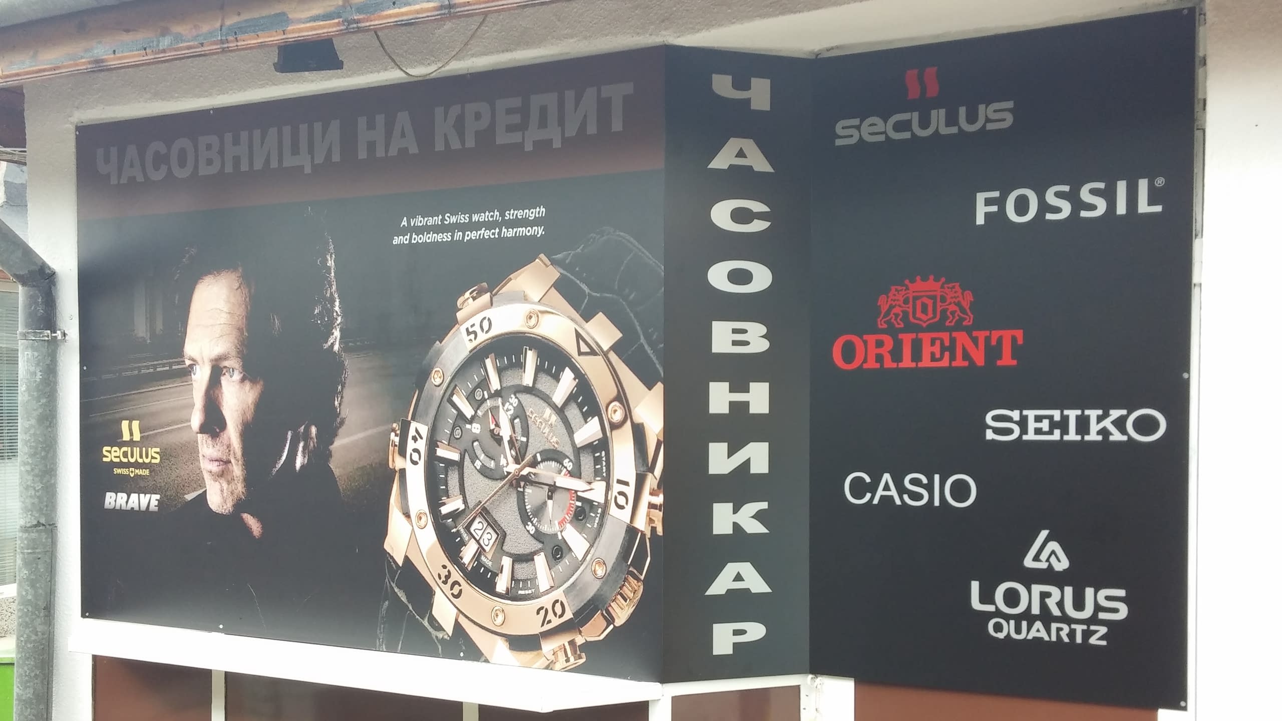 Ъглова рекламна табела за часовници с голямо изображение на часовник и списък с марки.