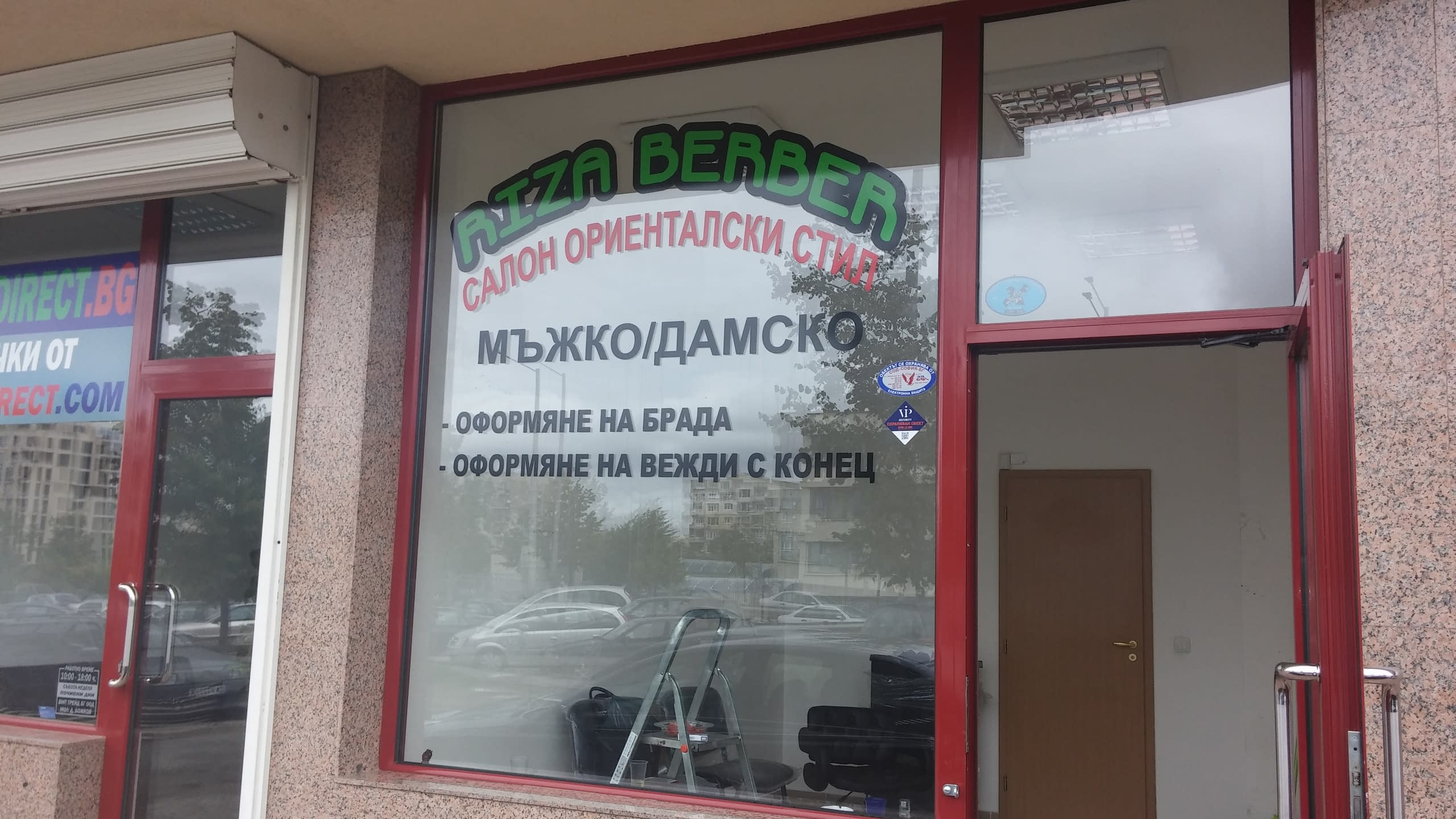 Витрина на салон с червена дограма и надписи от фолио с името на обекта и предлагани услуги.