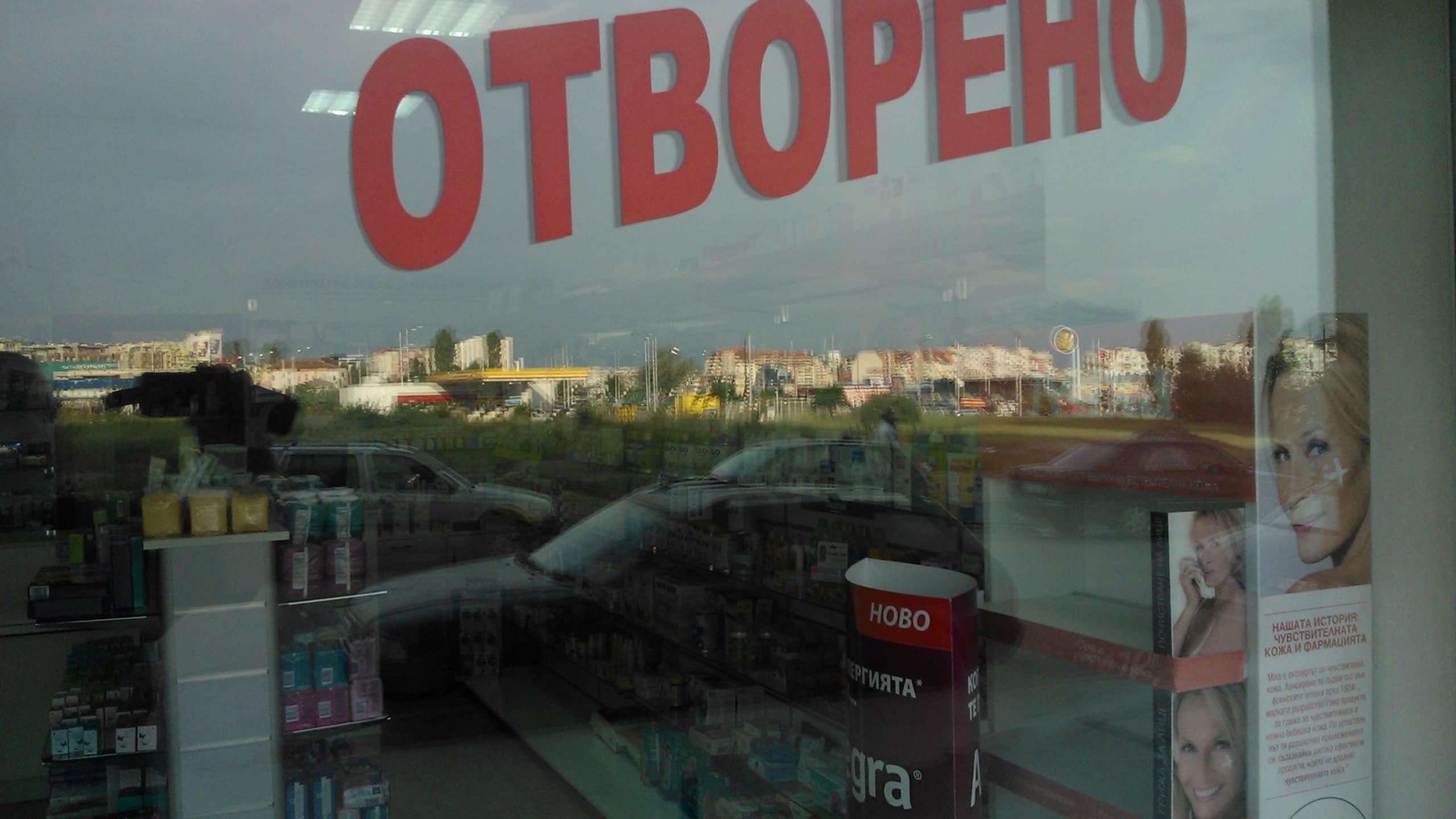 Голям червен надпис "Отворено" от фолио, залепен на стъклена витрина на магазин.