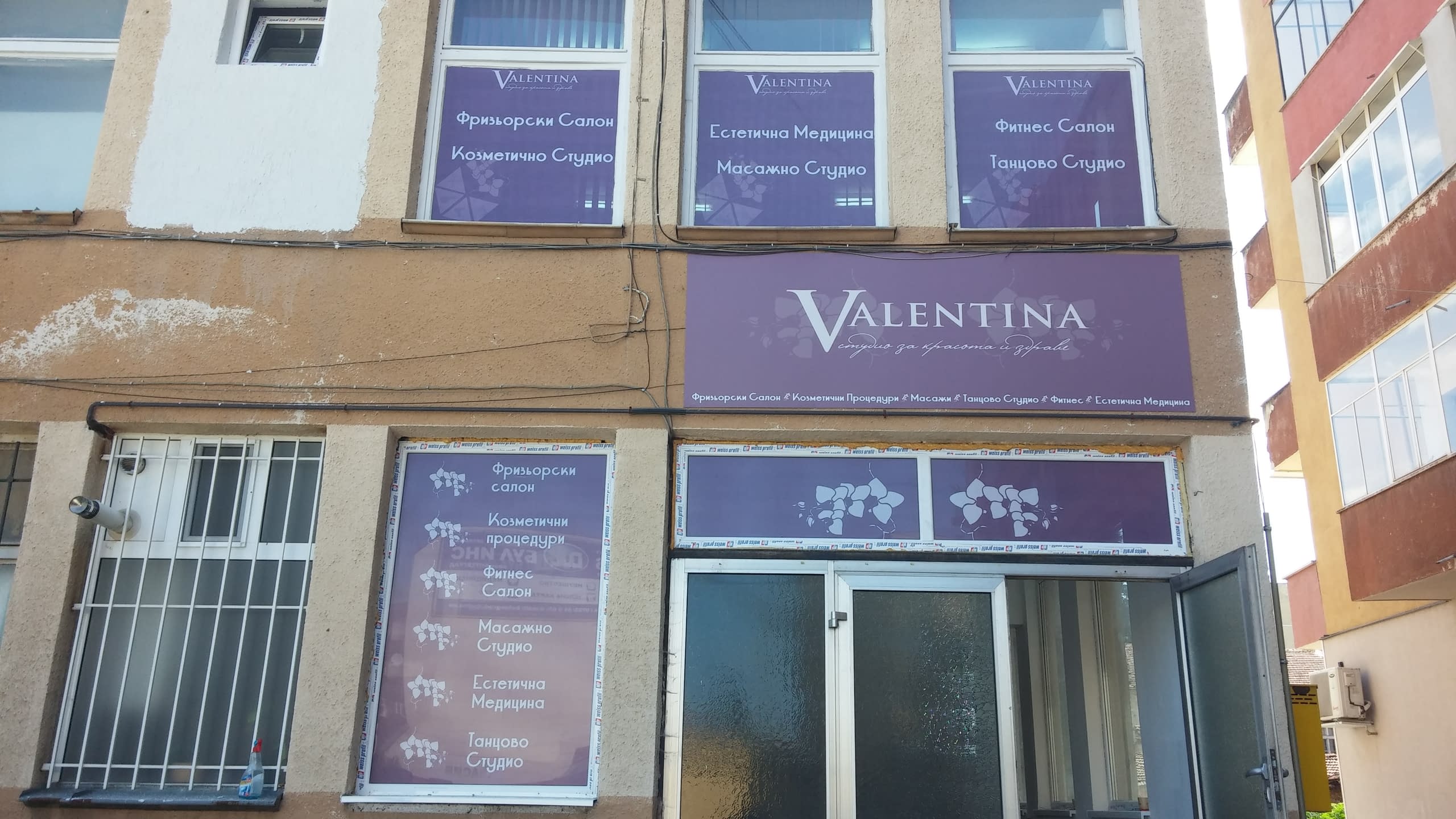 Външен изглед на студио "Valentina" с лилави надписи на прозорците на първия и втория етаж.