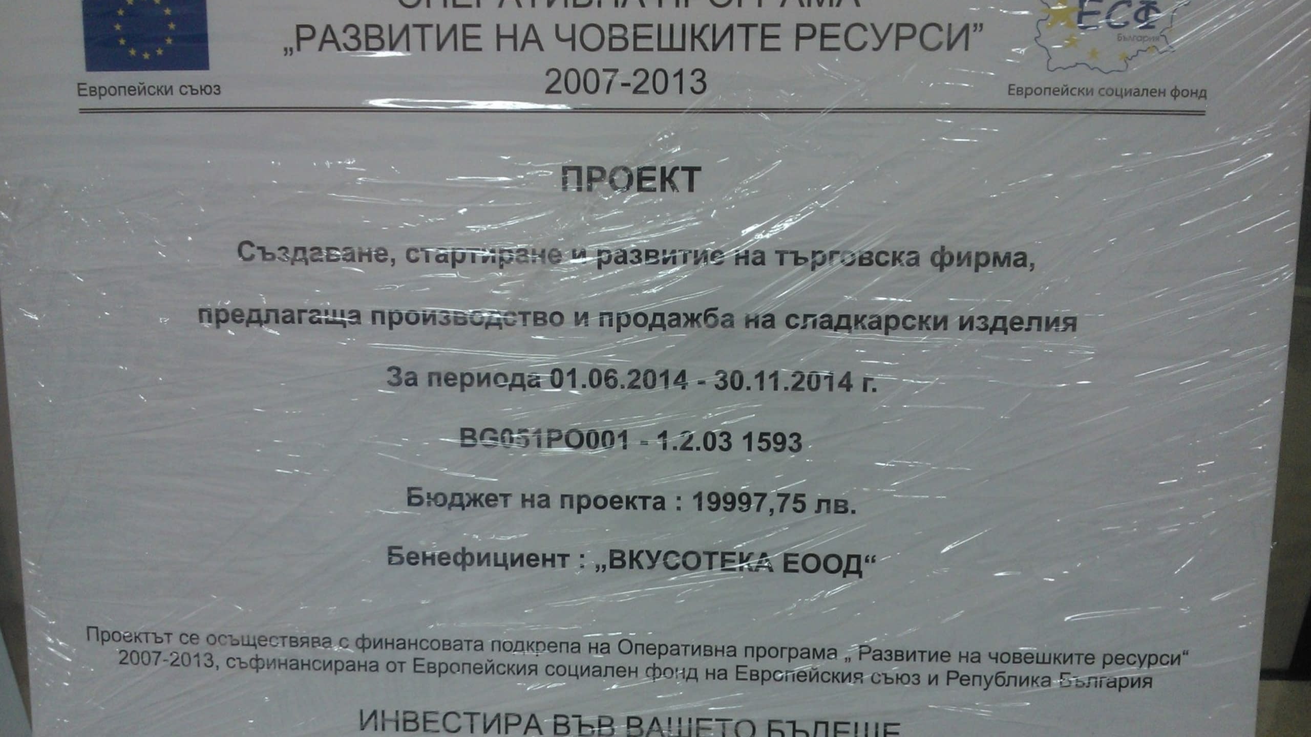 Информационна табела за проект по Оперативна програма 'Развитие на човешките ресурси', монтирана на стена.
