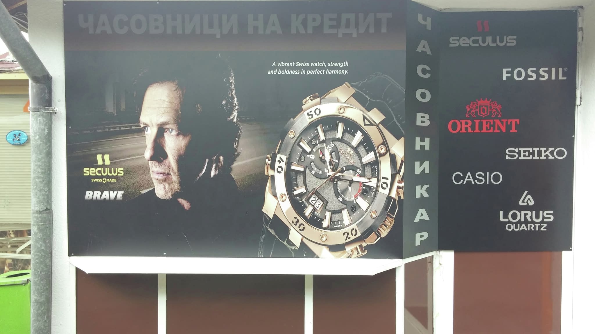 Рекламна табела за часовникар с мъжки портрет и голям часовник – промоция на марки Seiko, Casio, Fossil, Orient, Lorus.
