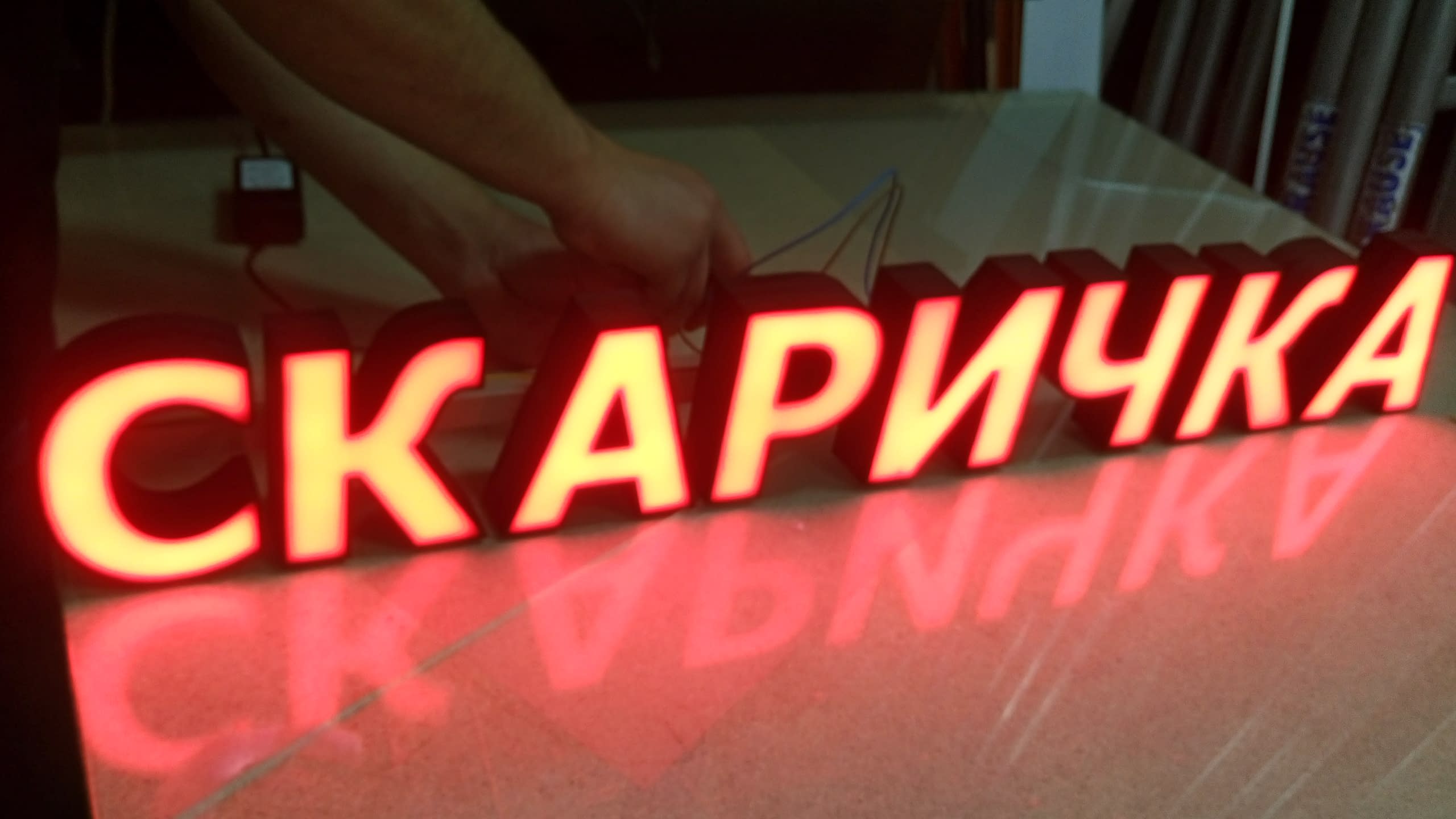 Изработка на светещи обемни букви с надпис "СКАРИЧКА", светещи в топло червено.