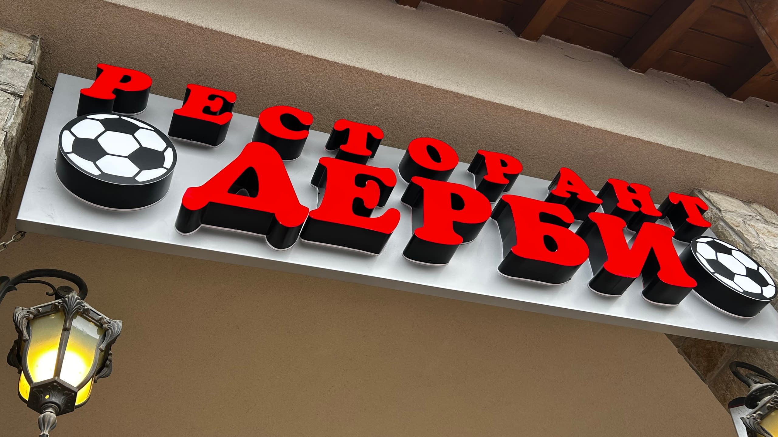 Рекламна табела на "Ресторант Дерби" с червени светещи обемни букви и декоративни елементи футболни топки.