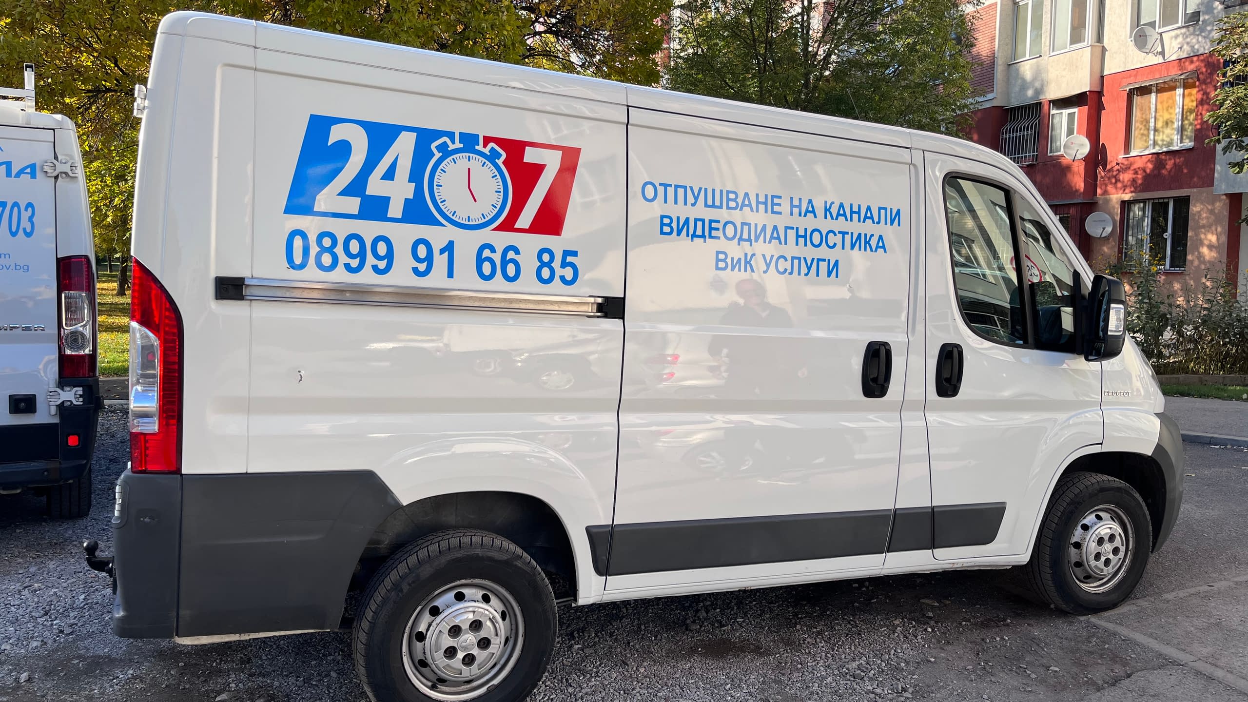 Динамично брандиране на бял товарен бус с рекламни графики в черно и оранжево. Частично облепване на автомобил за атрактивна мобилна реклама.