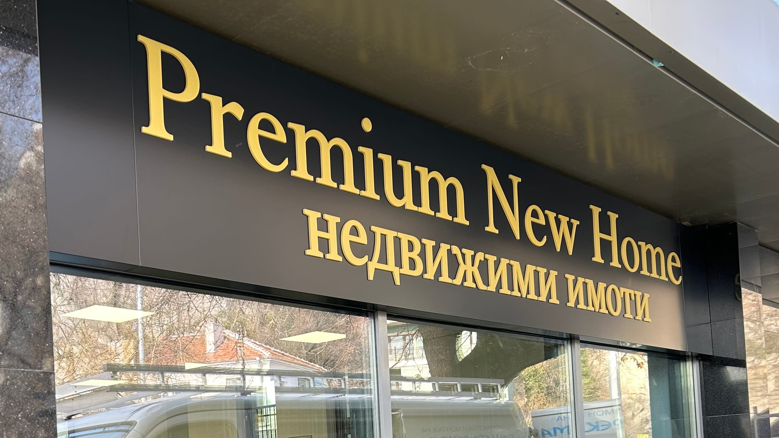 Стилни обемни букви в златист цвят за агенция за недвижими имоти "Premium New Home". Рекламен надпис върху черна табела, показващ качествена външна реклама за магазини и офиси.