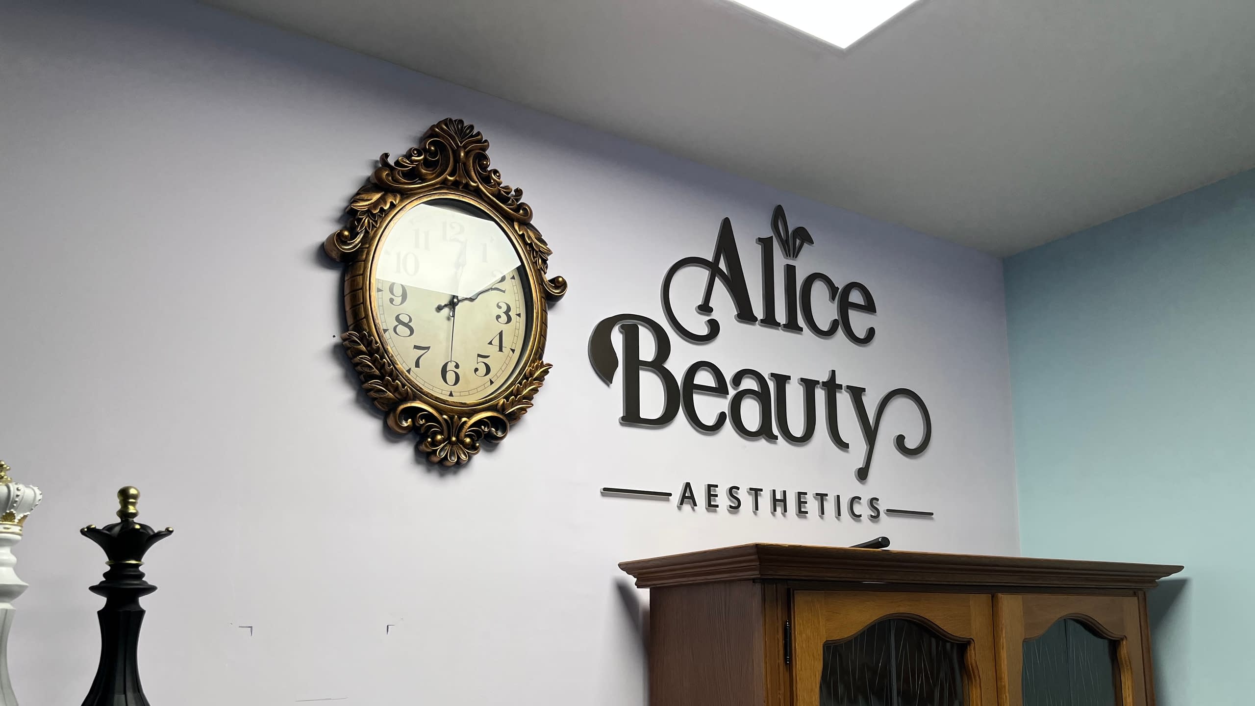 Елегантен интериорен надпис от черни обемни букви "Alice Beauty AESTHETICS" на стена в салон за красота. Стилна декорация и брандиране на интериора.