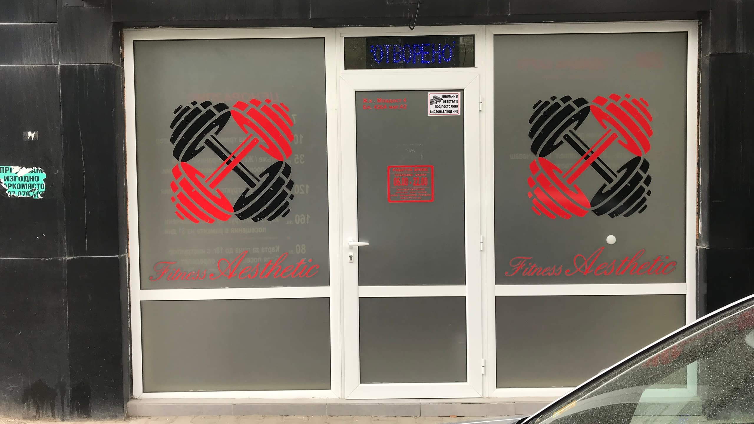 Брандиране на стъклена витрина на фитнес зала с матирано фолио. Декорация с изрязани по контур лога на дъмбели и надпис "Fitness Aesthetic" от червено и черно фолио.