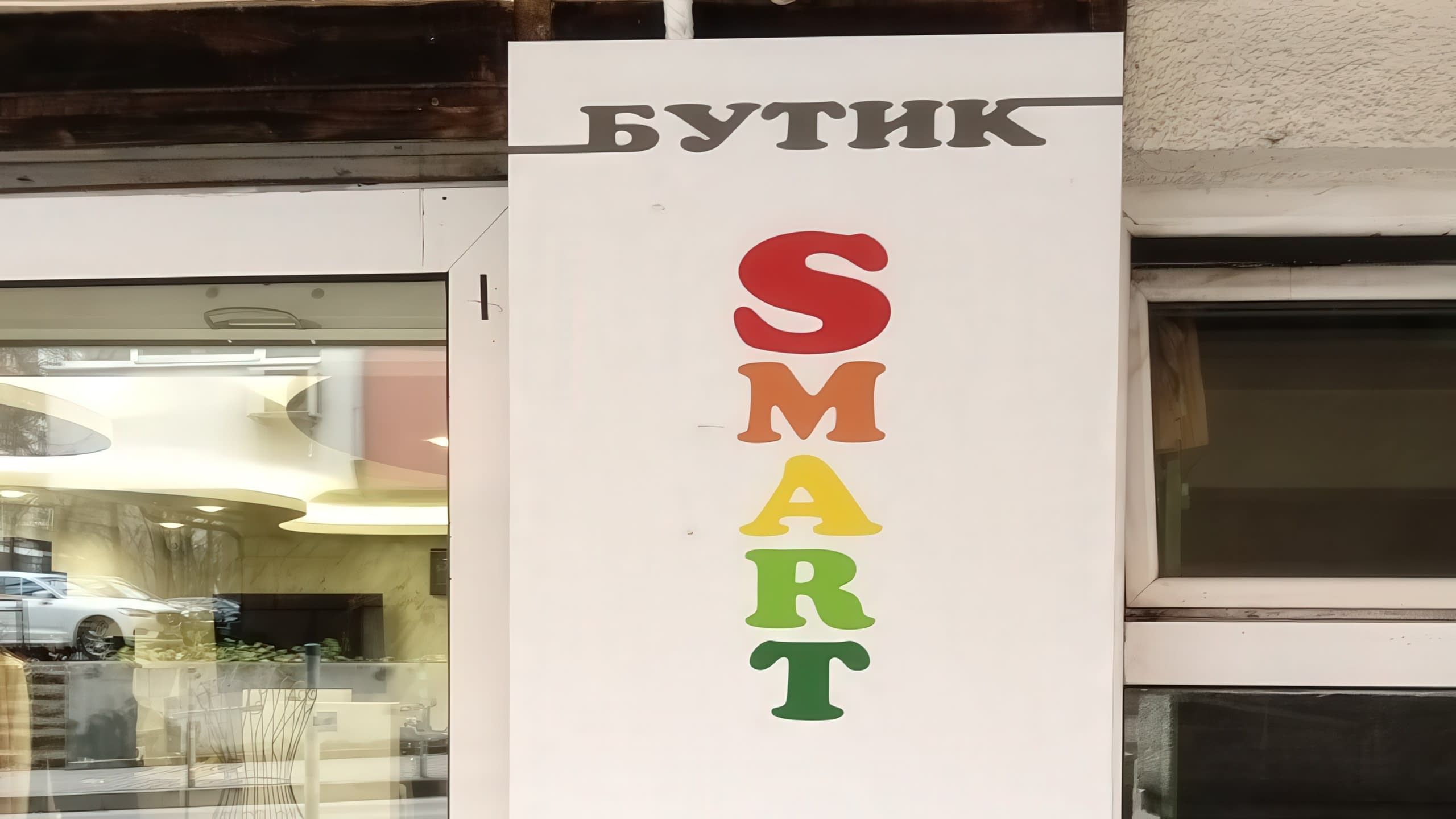 Рекламна табела на "Бутик SMART", изработена с цветно рязано фолио. Всяка буква от думата SMART е в различен ярък цвят.