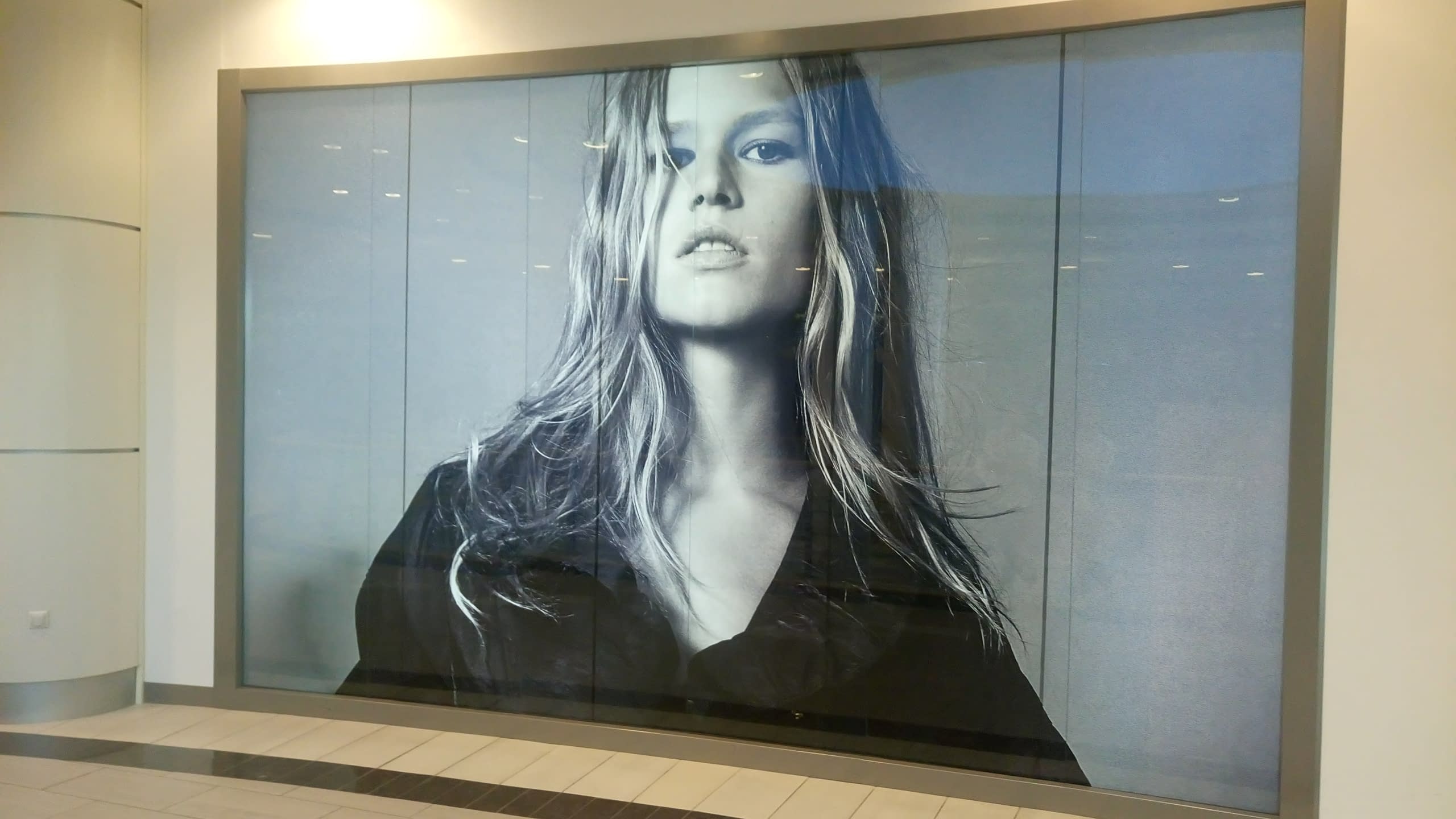 Голямоформатен печат върху рекламно платно за витрина на магазин. Черно-бяла фотография на жена, използвана за интериорна декорация и реклама.