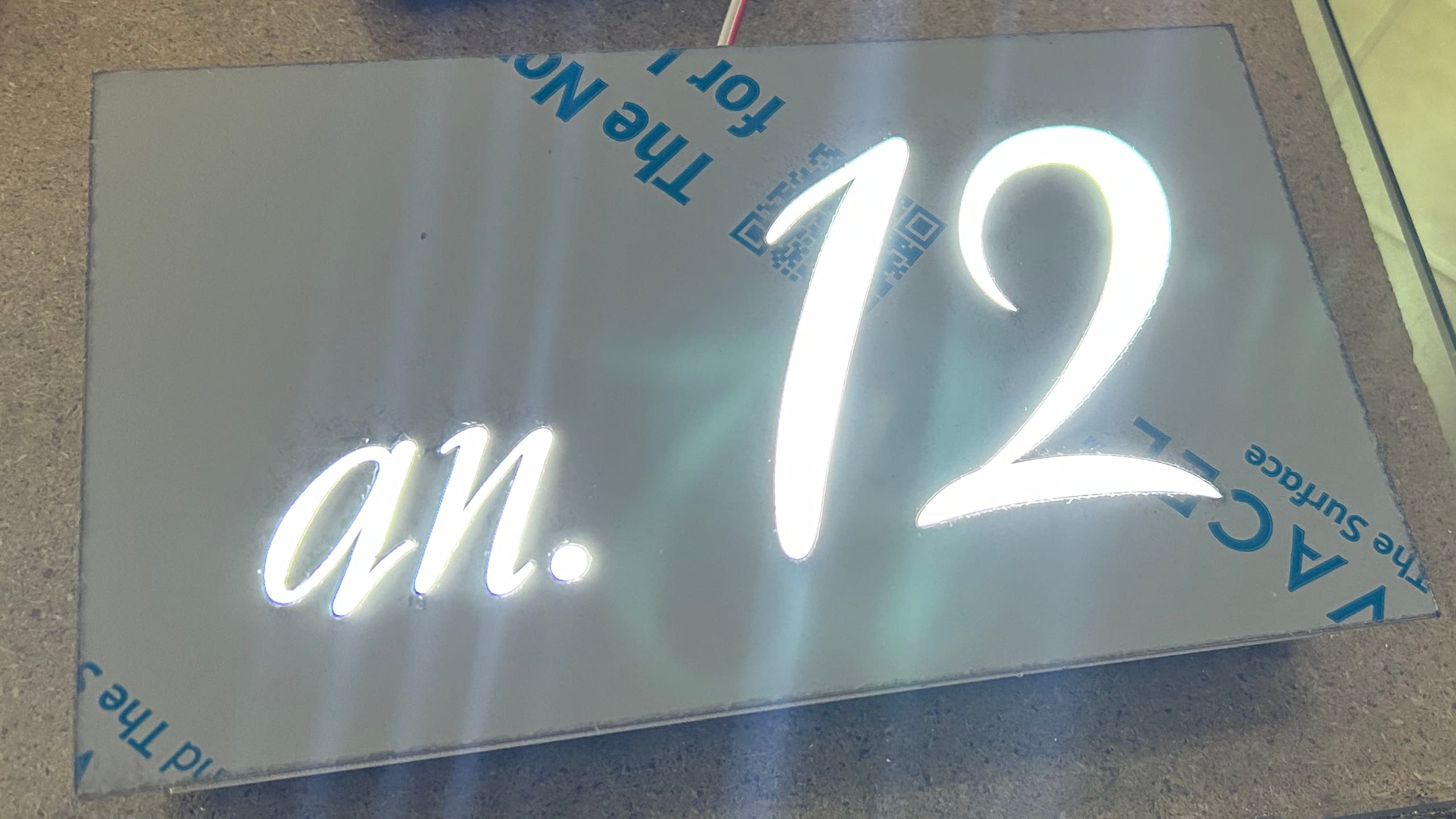 Елегантна светеща табела от еталбонд в процес на изработка с номер на апартамент "ап. 12", изрязан и светещ с бяла светлина.