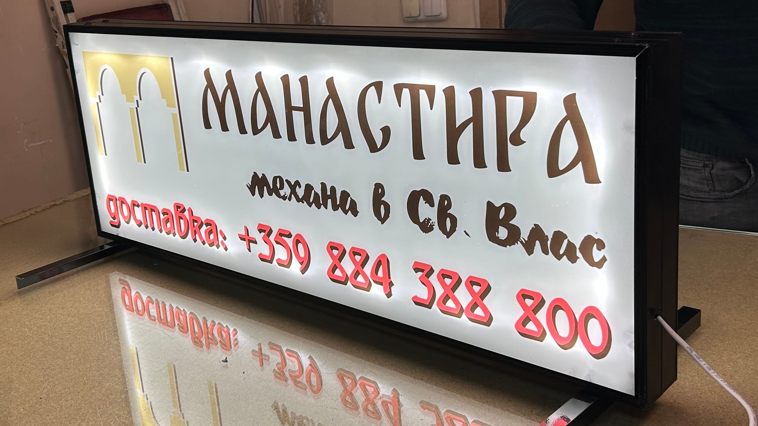 Светеща рекламна табела за покрив на автомобил, рекламираща доставки от "Механа Манастира" в Свети Влас, с изписан телефонен номер.