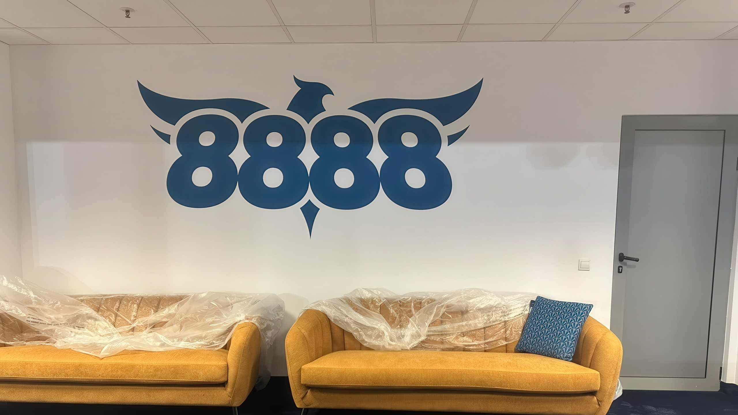 Интериорна декорация на стена в офис с голямо лого "8888", изрязано от синьо фолио.