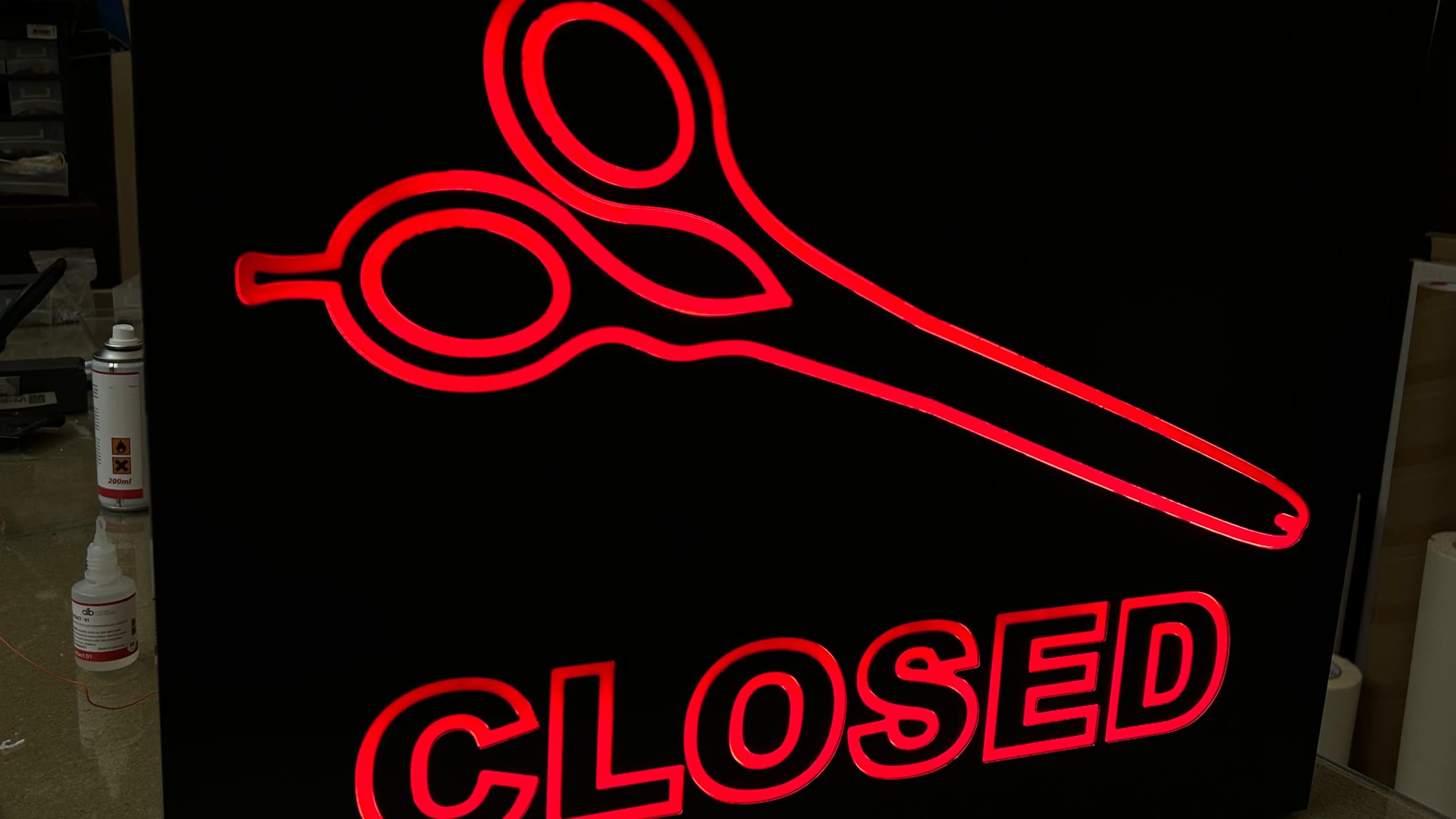 Светеща интериорна табела "Closed" с икона на ножица в червено, подходяща за фризьорски салон.