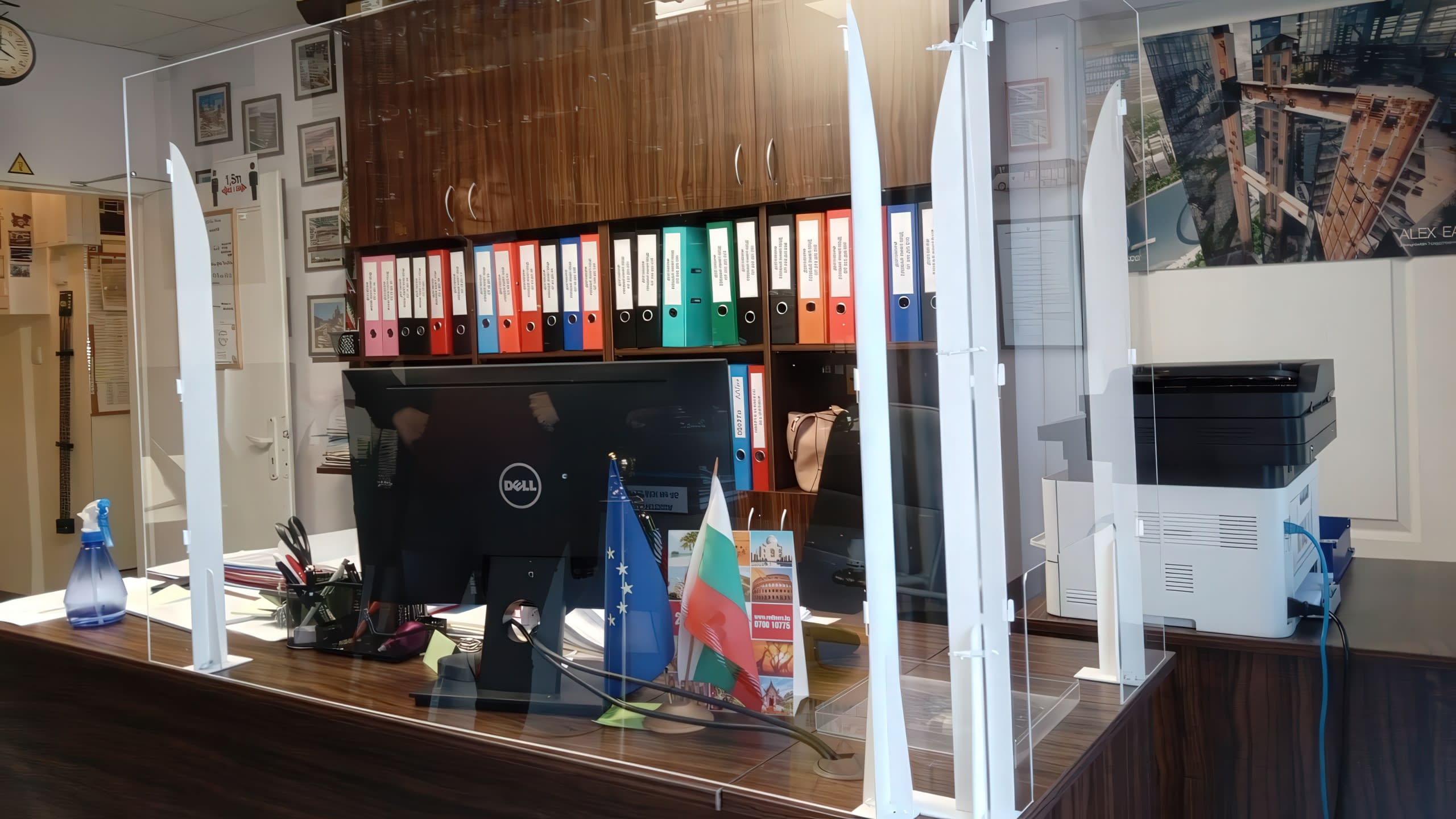 Рецепция в офис, обезопасена със защитна преграда от плексиглас със стилни бели стойки.